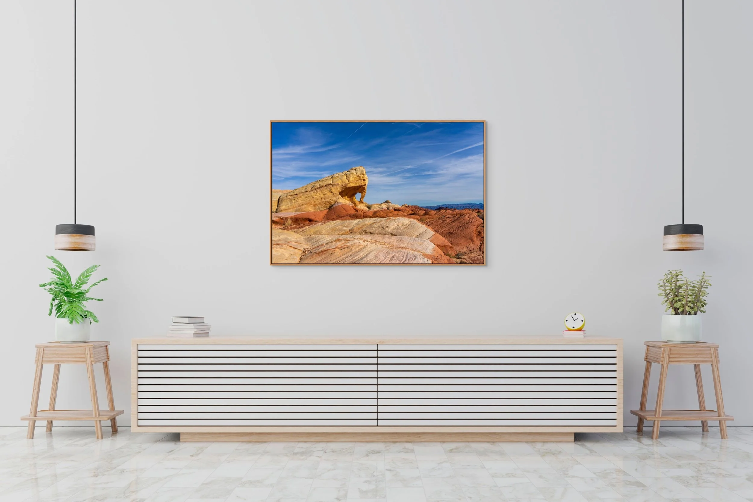 The Unmapped Eye in a floating Natural Oak frame above a minimalist white sideboard with pendant lights and a potted plant.