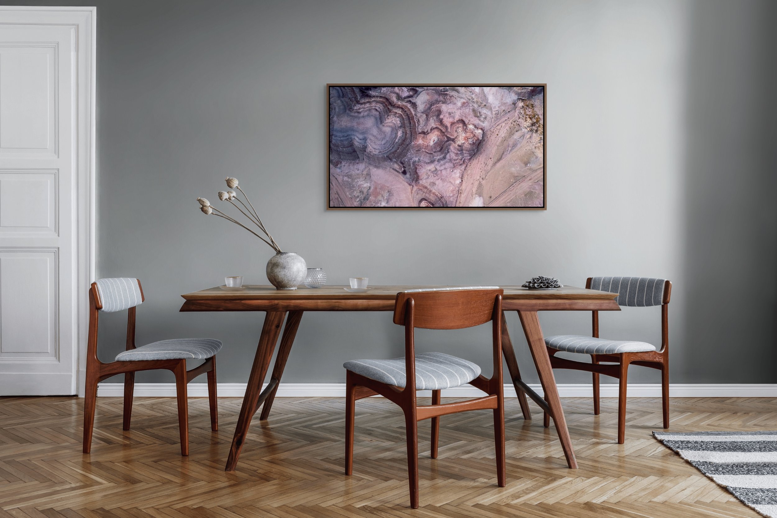 Small in Time — aerial bentonite-hill patterns in mauve and cream, framed in walnut floating wood frame in a dining room setting.