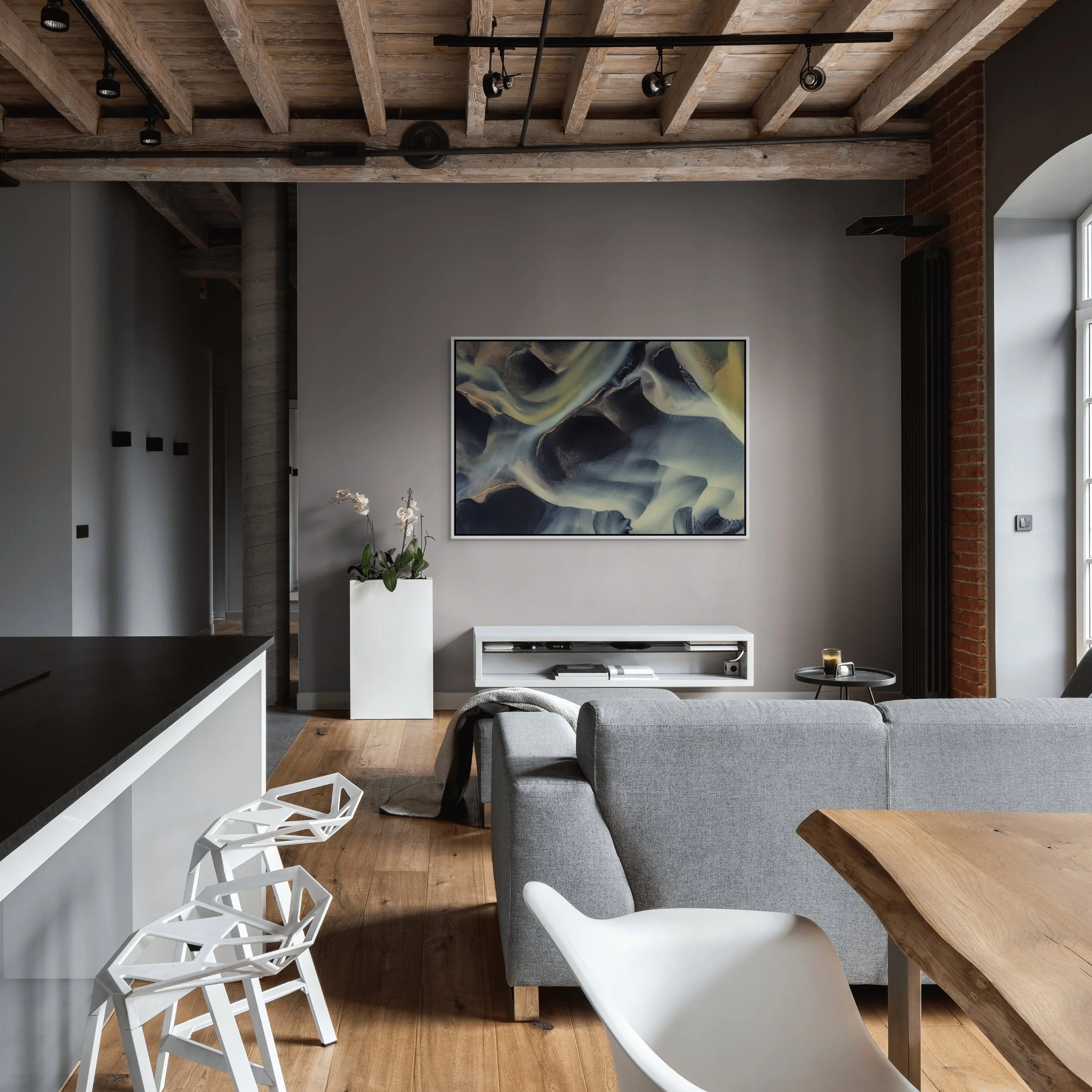 Framed in White — River of Shadows in an industrial loft with exposed beams, grey sofa, and dining area.