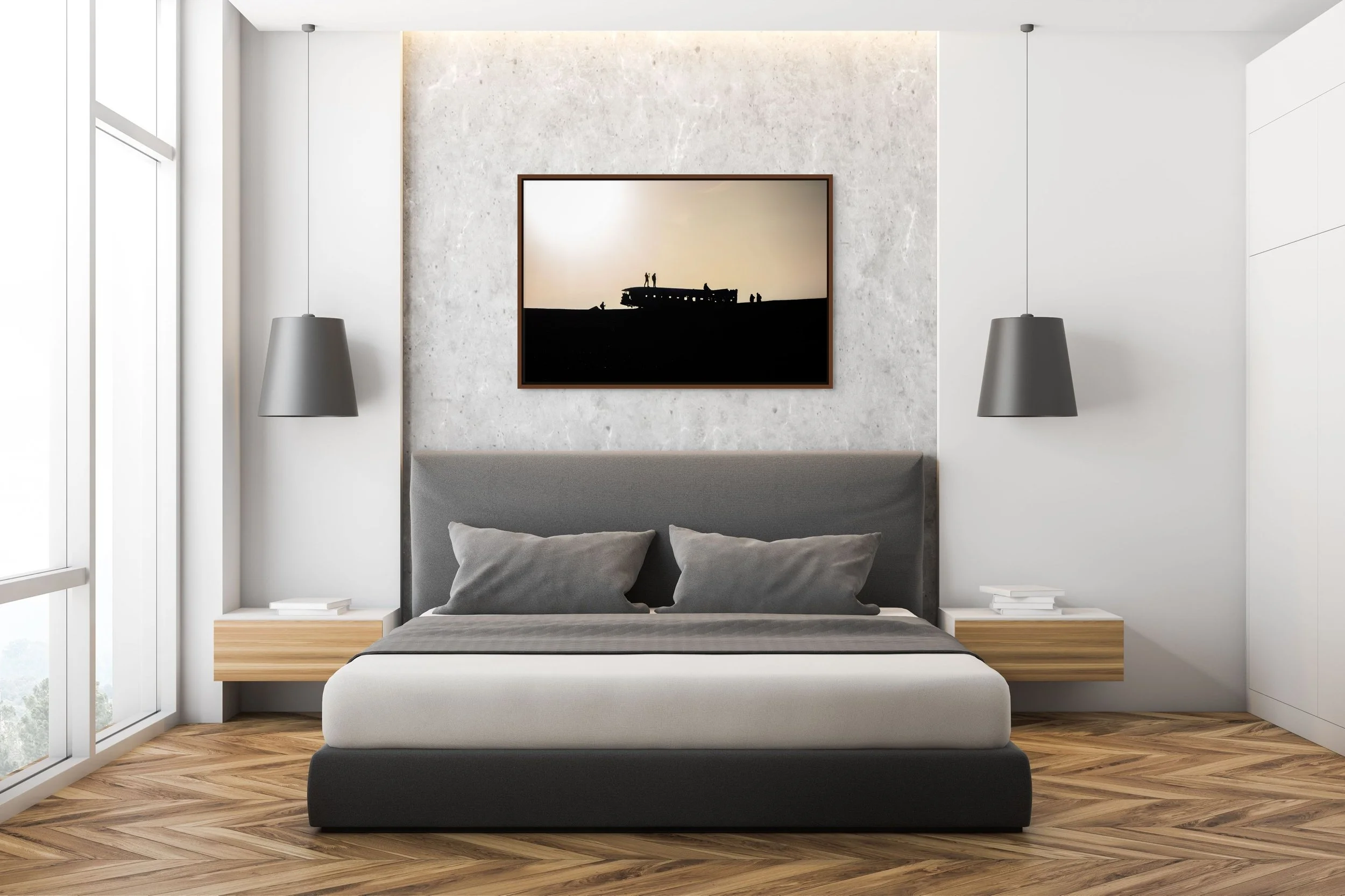 Echoes in the Wreck — DC-3 wreck silhouettes on Iceland’s black-sand plain; framed in alder brown floating wood frame in a modern bedroom with marble feature wall and bedside lamps.