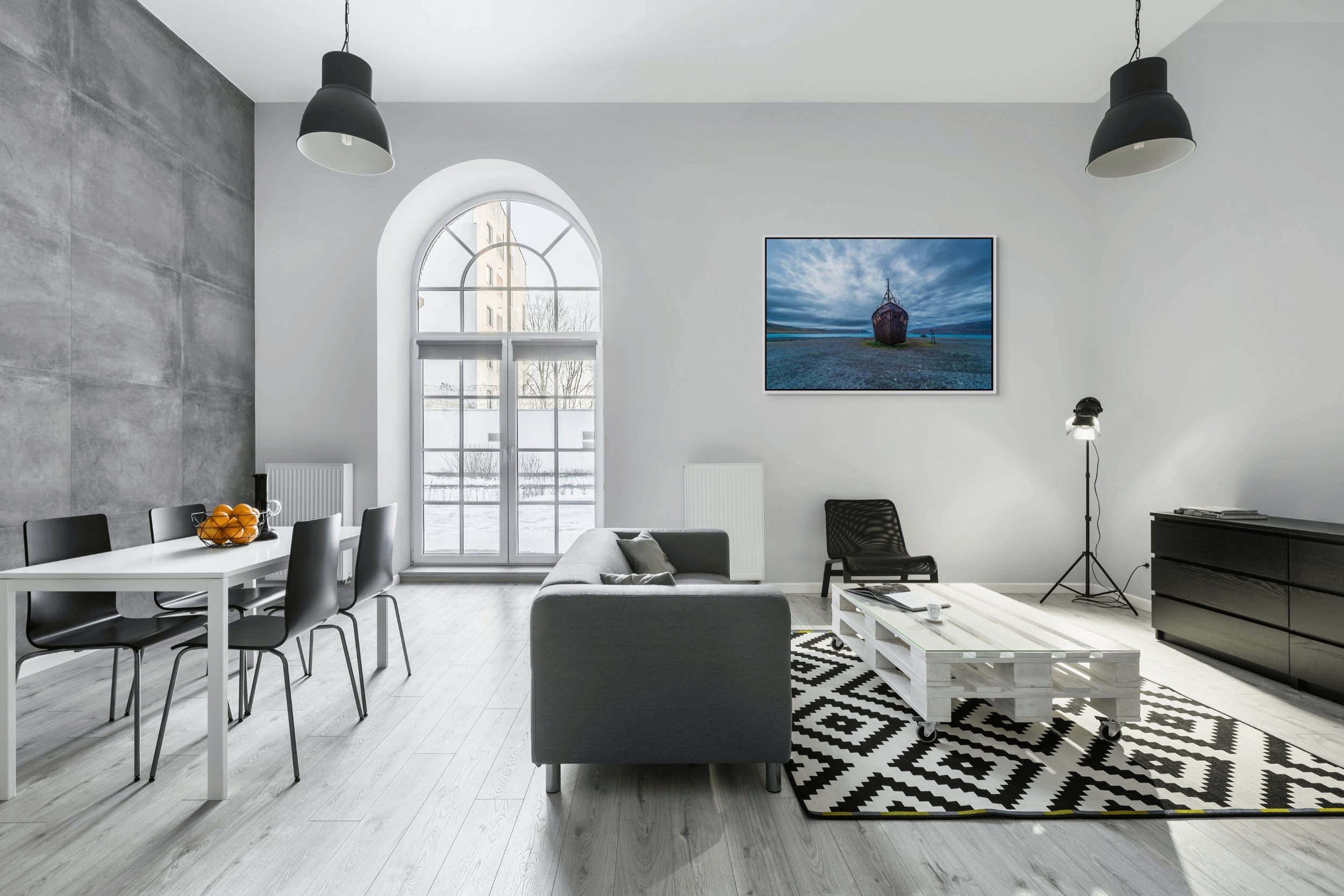 The Last Voyage in a white floating frame frame shown in an industrial loft with an arched window and black-and-white seating.