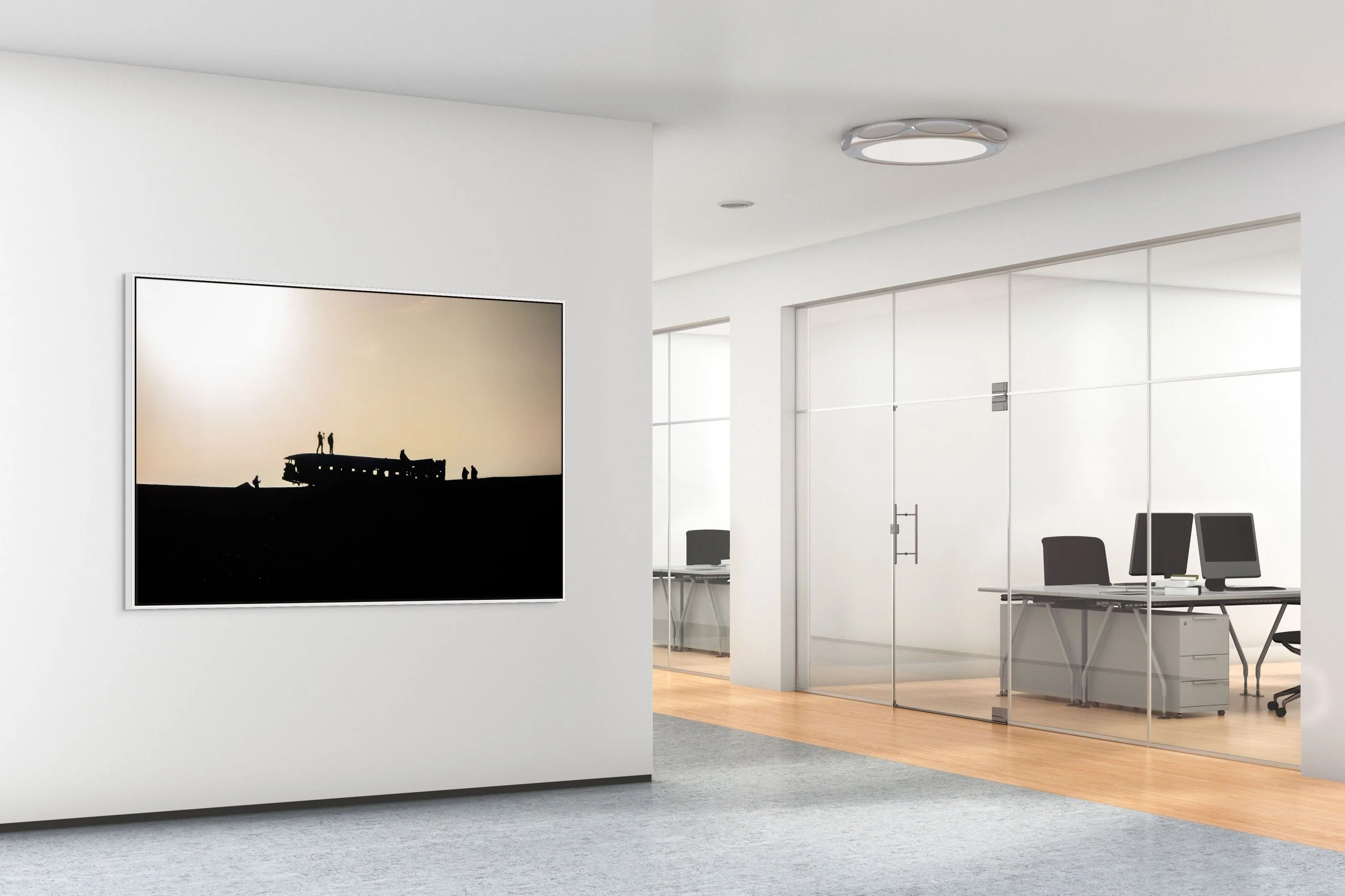 Echoes in the Wreck — DC-3 wreck silhouettes on Iceland’s black-sand plain; framed in white floating wood frame in a contemporary office lobby with glass partitions.