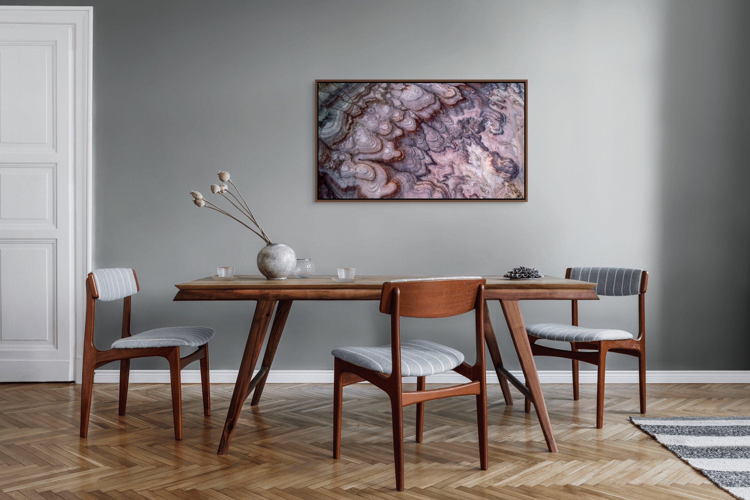 Layers of Time framed in floating wood — alder brown; abstract violet-ochre layers above a warm dining room table and chairs.