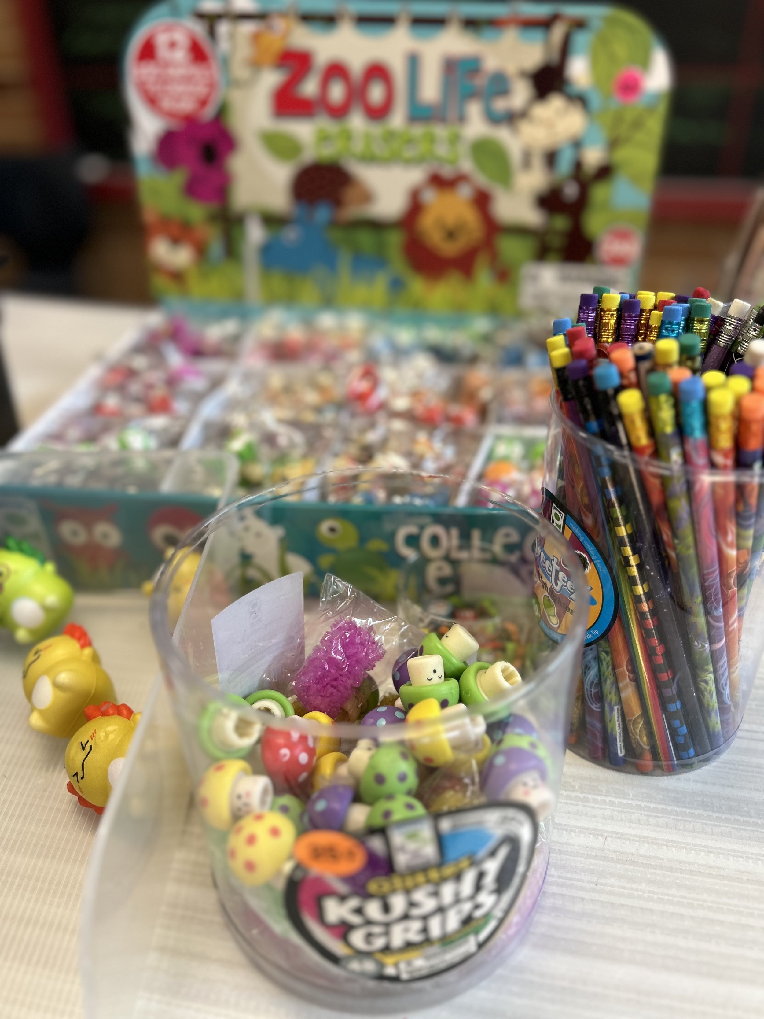 A close view of fun items for sale like zoo animal keychains, brightly colored pencils, and cushy pencil grips.