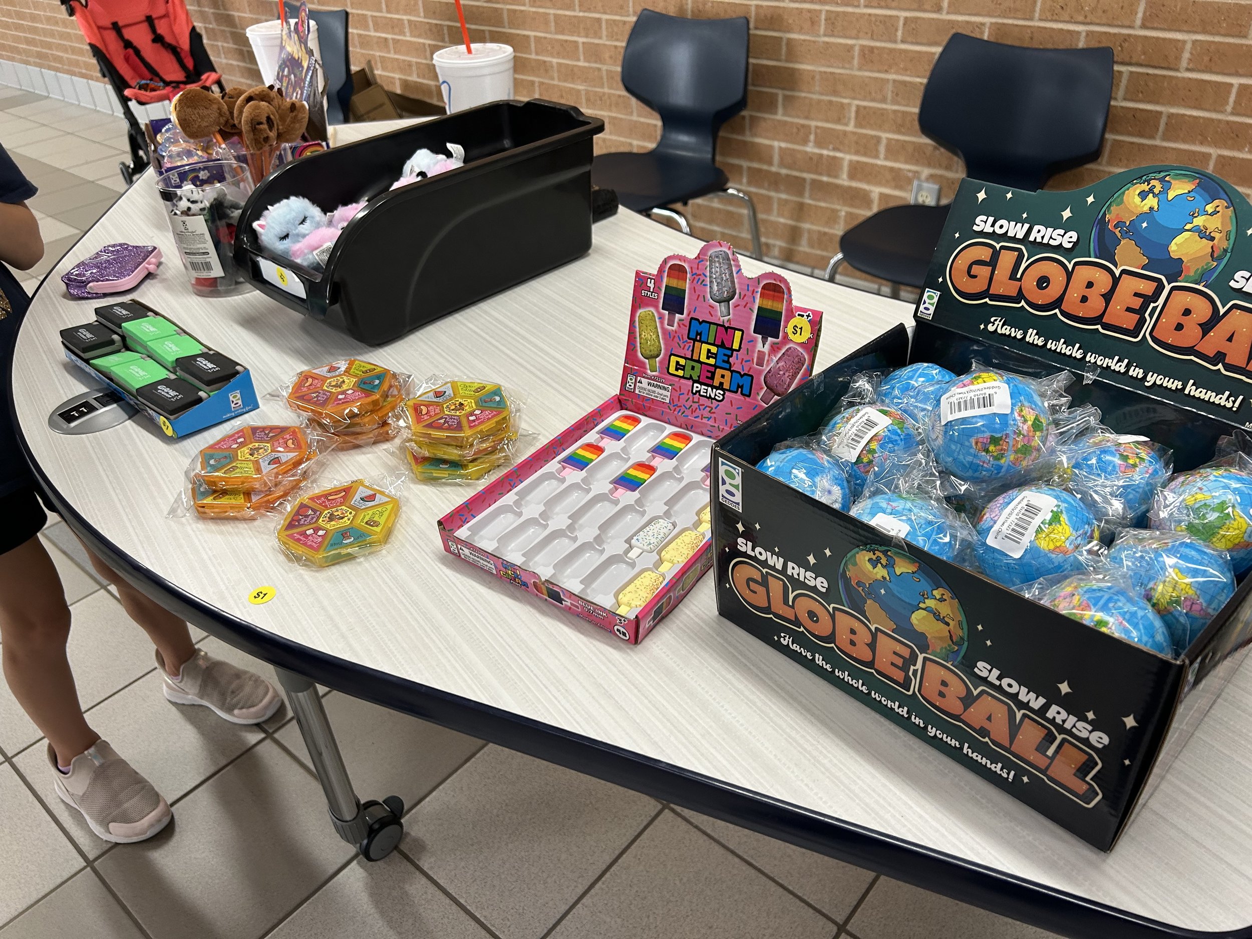 A Spirit Shack table with different items like a squishy globe ball, scented erasers, and pens shaped like brooms.