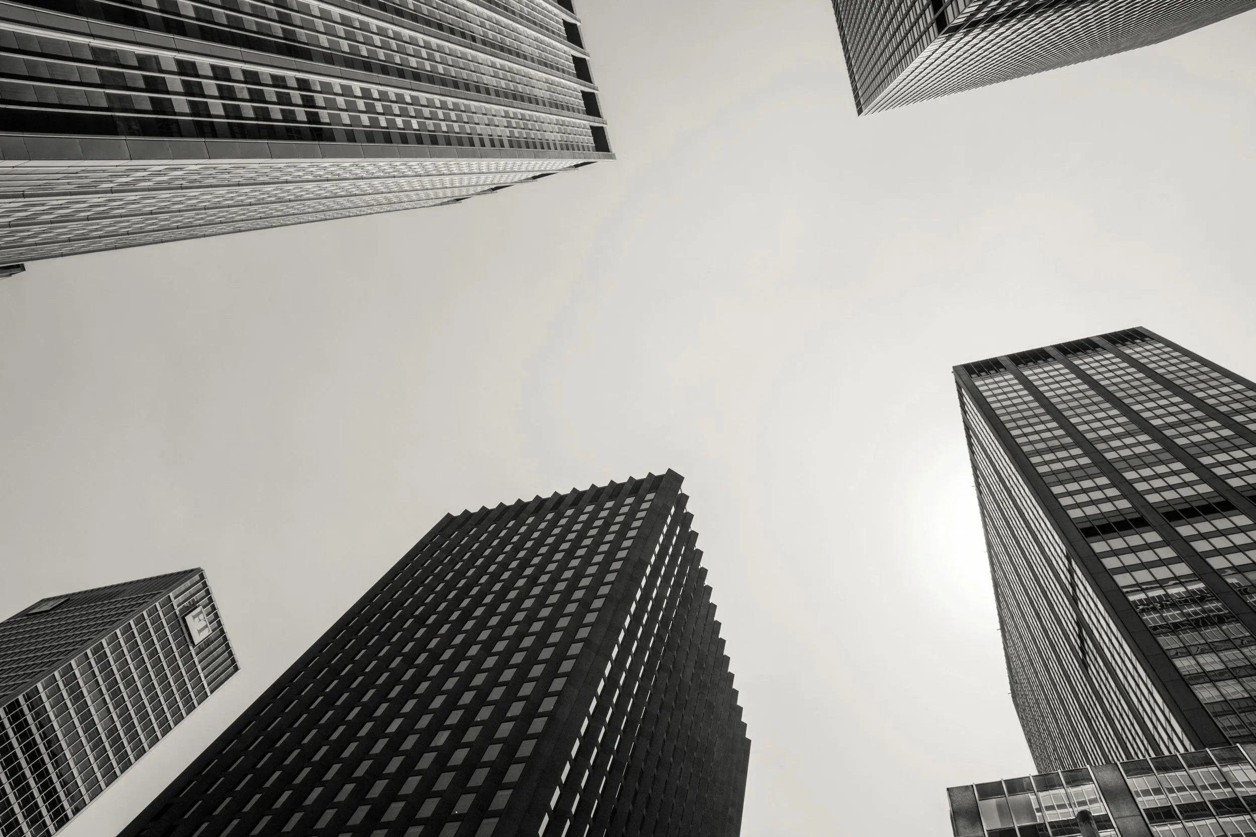 Black and white photo of tall skyscrapers viewed from the ground looking up at the sky.