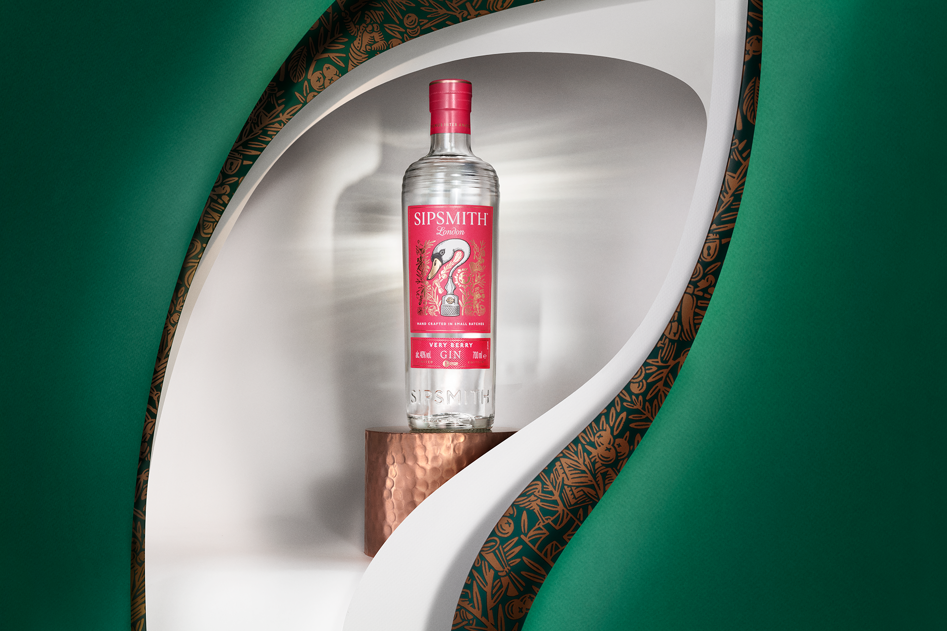 A bottle of Sipsmith London gin with a pink label featuring a swan design, displayed on a copper-colored pedestal inside a white niche, framed by green decorative structures.