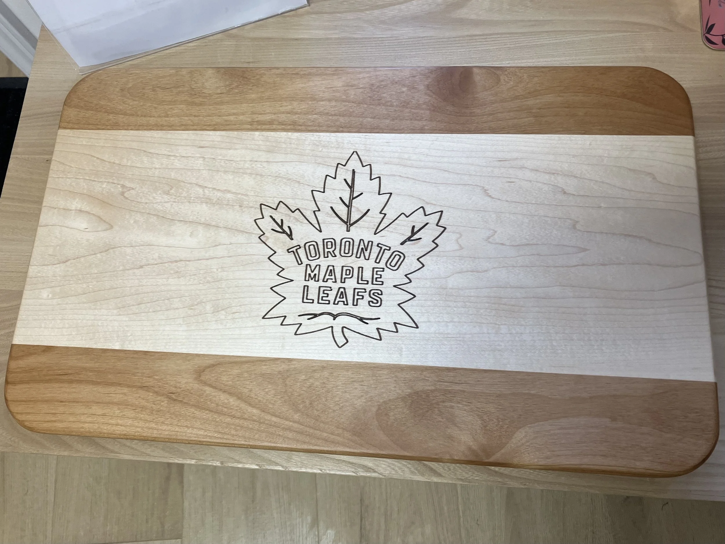 Wooden tray with a white strip running across the middle and a Toronto Maple Leafs logo printed on it, featuring a maple leaf and the team name.