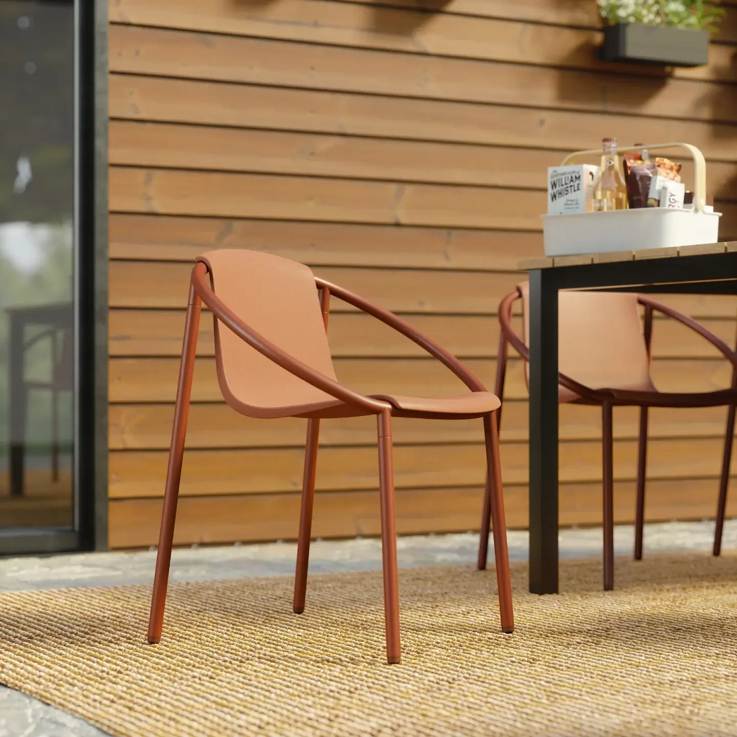 Outdoor patio area with a tan chair, black table, and a white basket on top of the table, against a wooden wall.