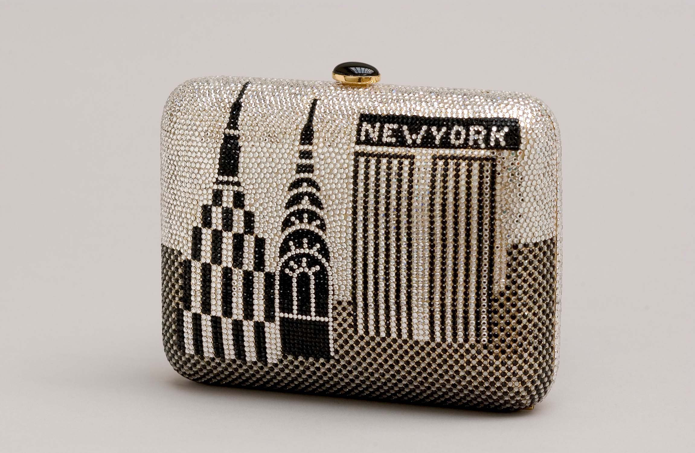 A designer clutch purse covered in crystals, featuring a NYC skyline and bar code pattern with the word 'New York' at the top.