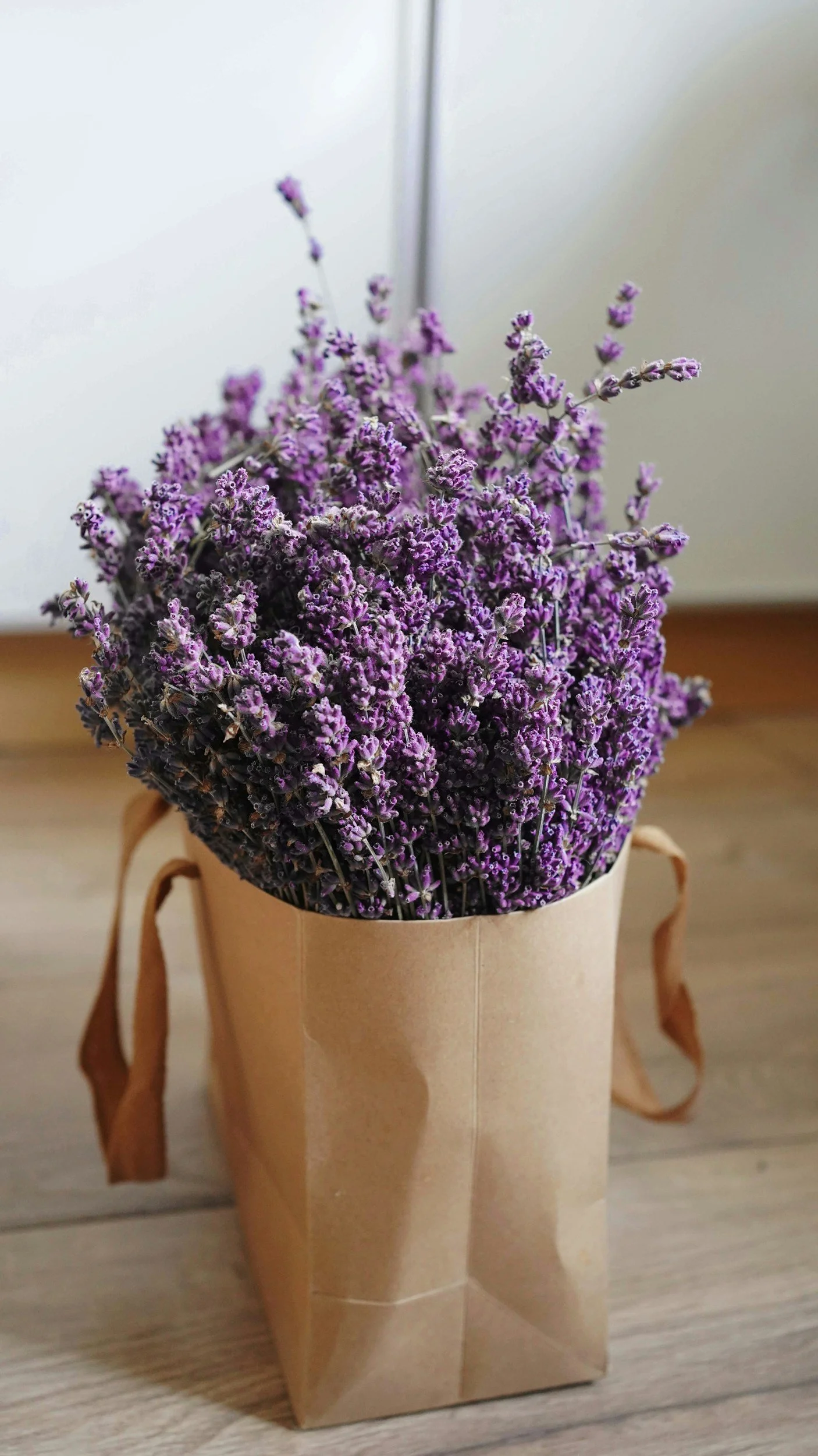 A paper bag filled with purple lavender flowers placed on a wooden surface.