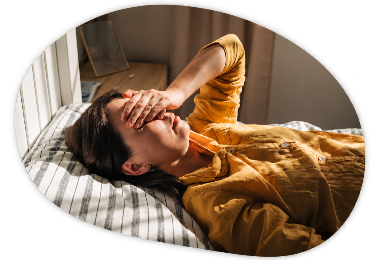 Woman lying in bed covering her eyes, representing trauma-informed hypnotherapy in Orlando