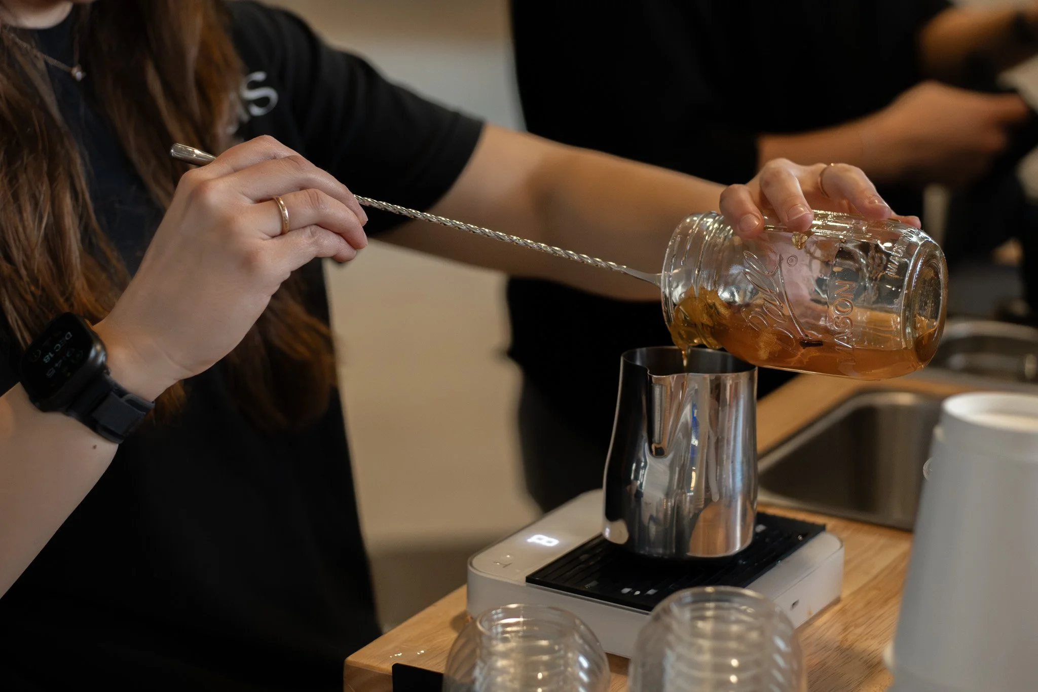 Close-up of coffee being poured from an espresso machine into a clear glass cup.