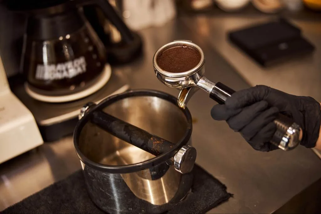 Close-up of coffee being poured from an espresso machine into a clear glass cup.