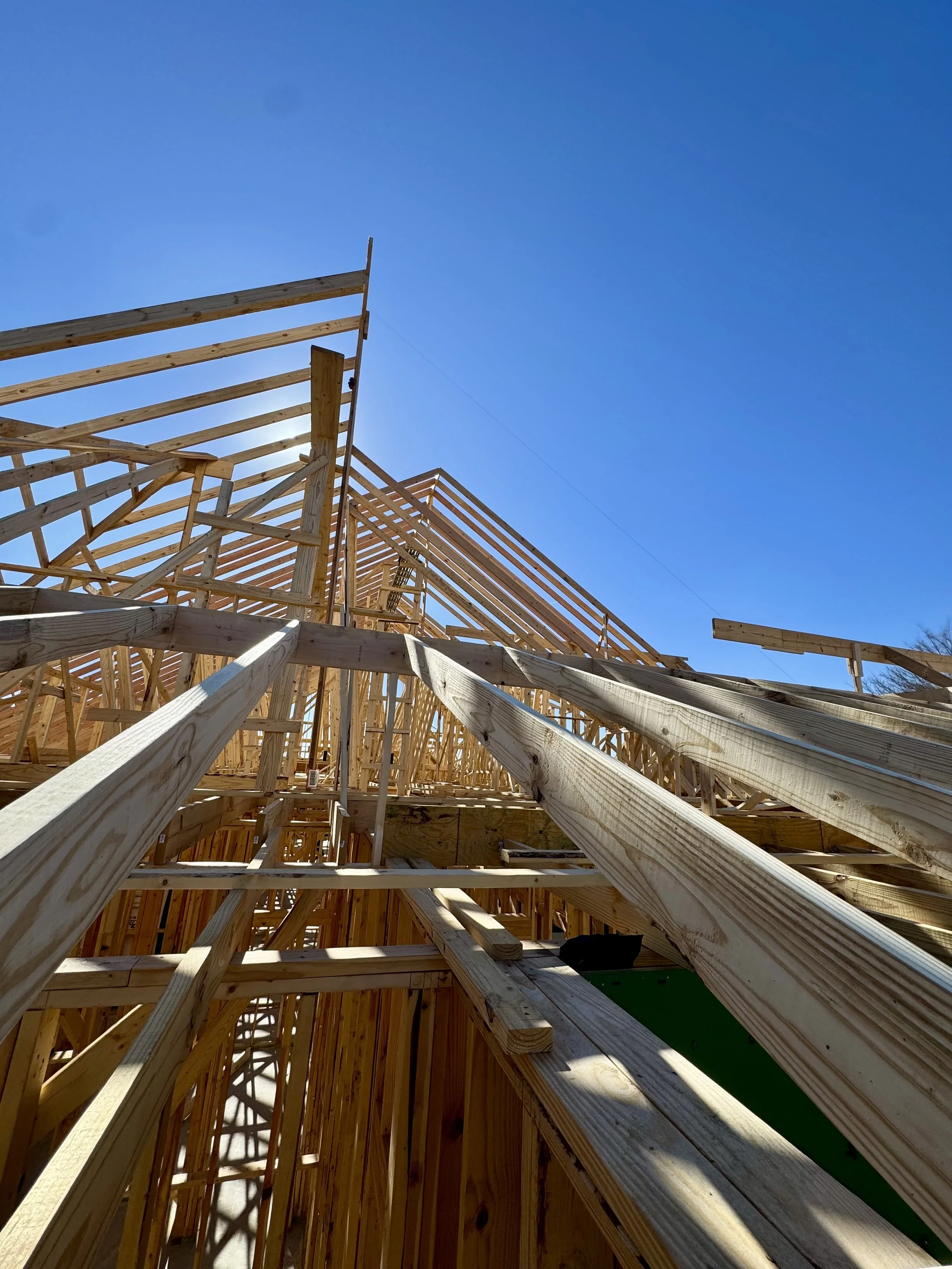 Wooden framing for a building under construction against a clear blue sky.