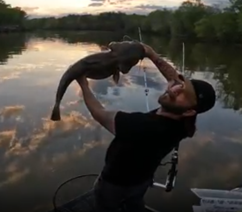 Fishing Guide Dustin Schmidt of Lake Weiss Destinations holding a large fish over water at sunset, on a boat on Coosa River Alabama on Georgia border at Weiss Lake