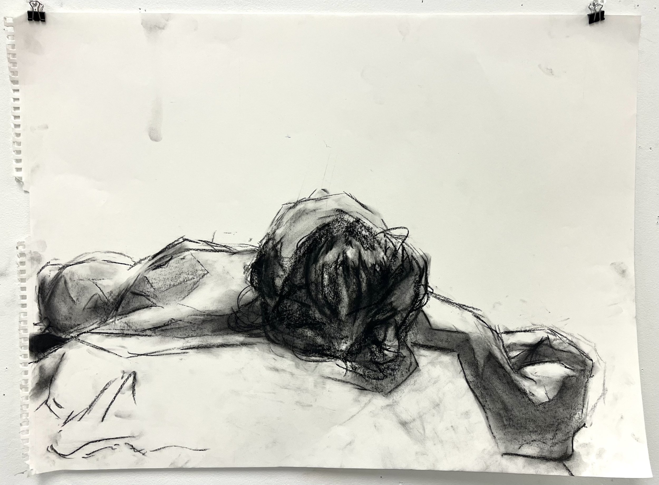 Sketch of a person lying face down on a surface, with their head turned to the side and one arm extended outward.
