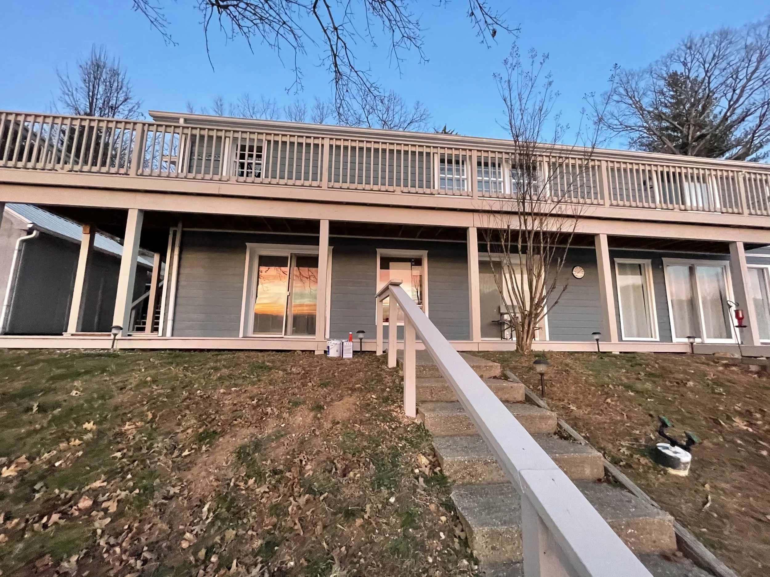 Multi-level white wood deck and railing painted by Quality Control Painting on a navy blue lakefront home in Lake Ozark.