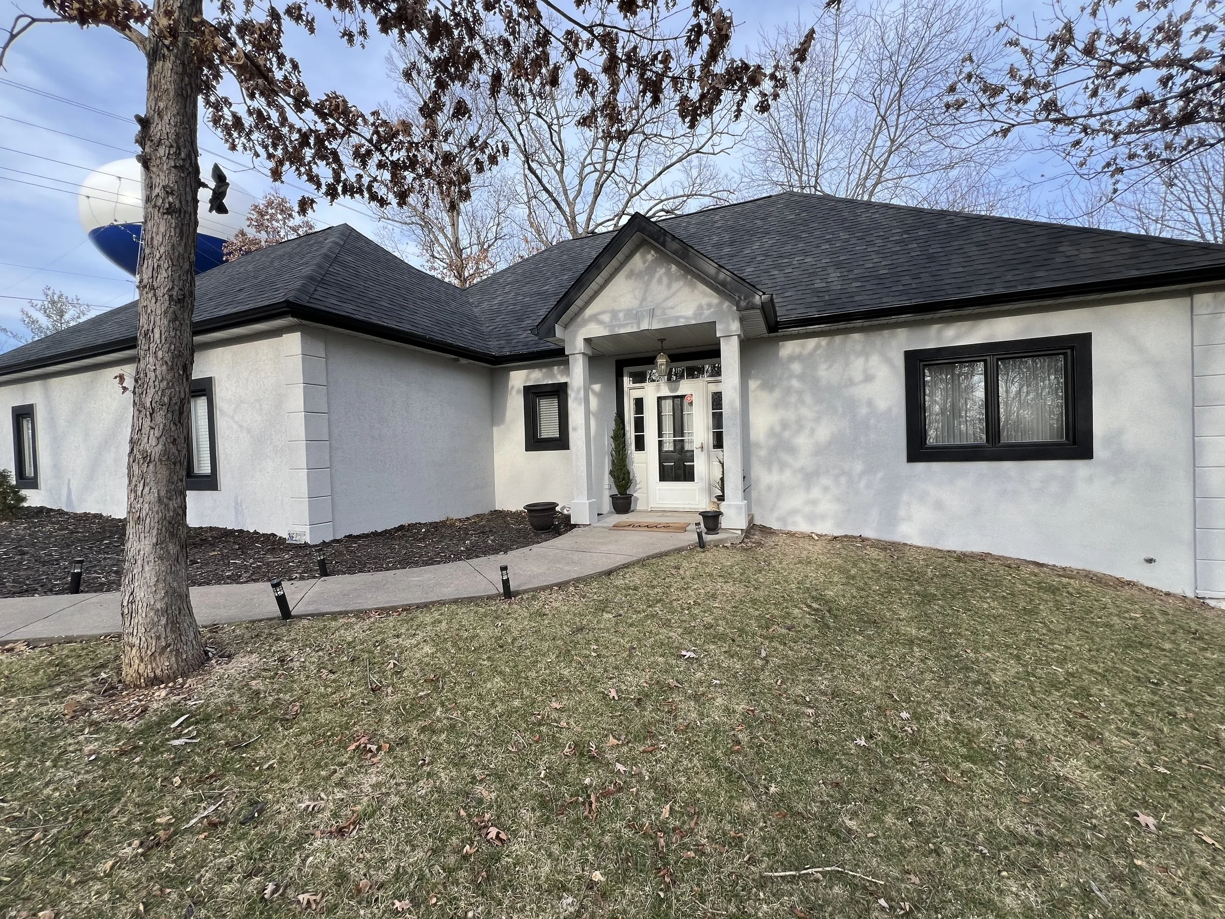 Modern stucco exterior painting with black window trim in the Village of Four Seasons by Quality Control Painting.