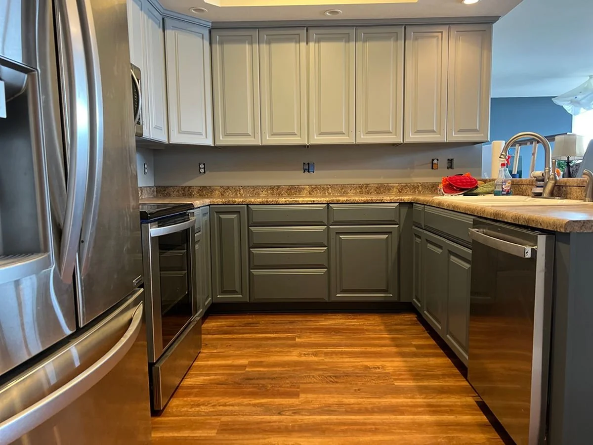 Modern kitchen transformation by Quality Control Painting in Lake Ozark featuring two-tone grey and charcoal professionally painted cabinets with a smooth factory-grade finish.