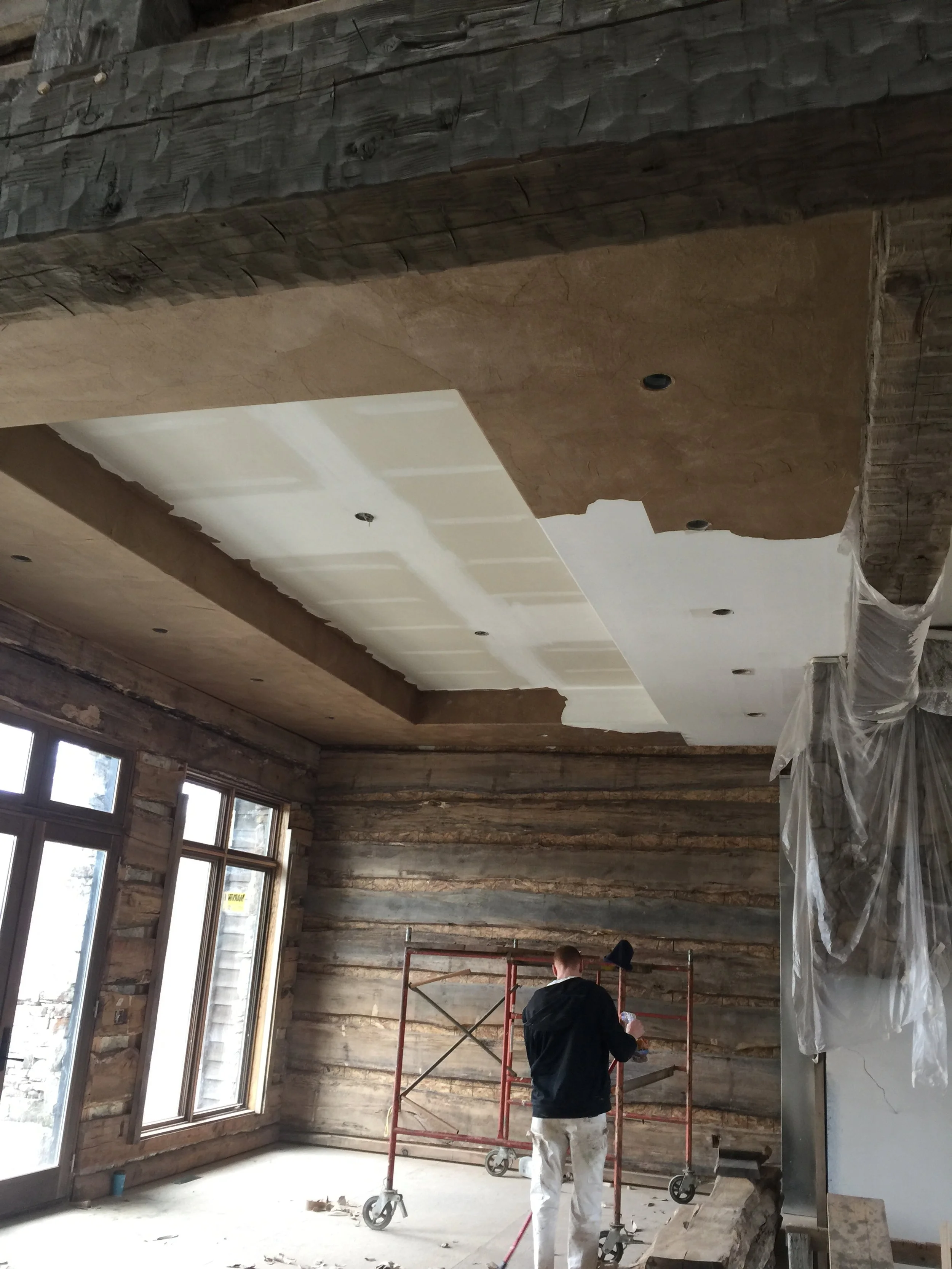 Professional painters on scaffolding prepping a large vaulted log home ceiling for Quality Control Painting in Gravois Mills.