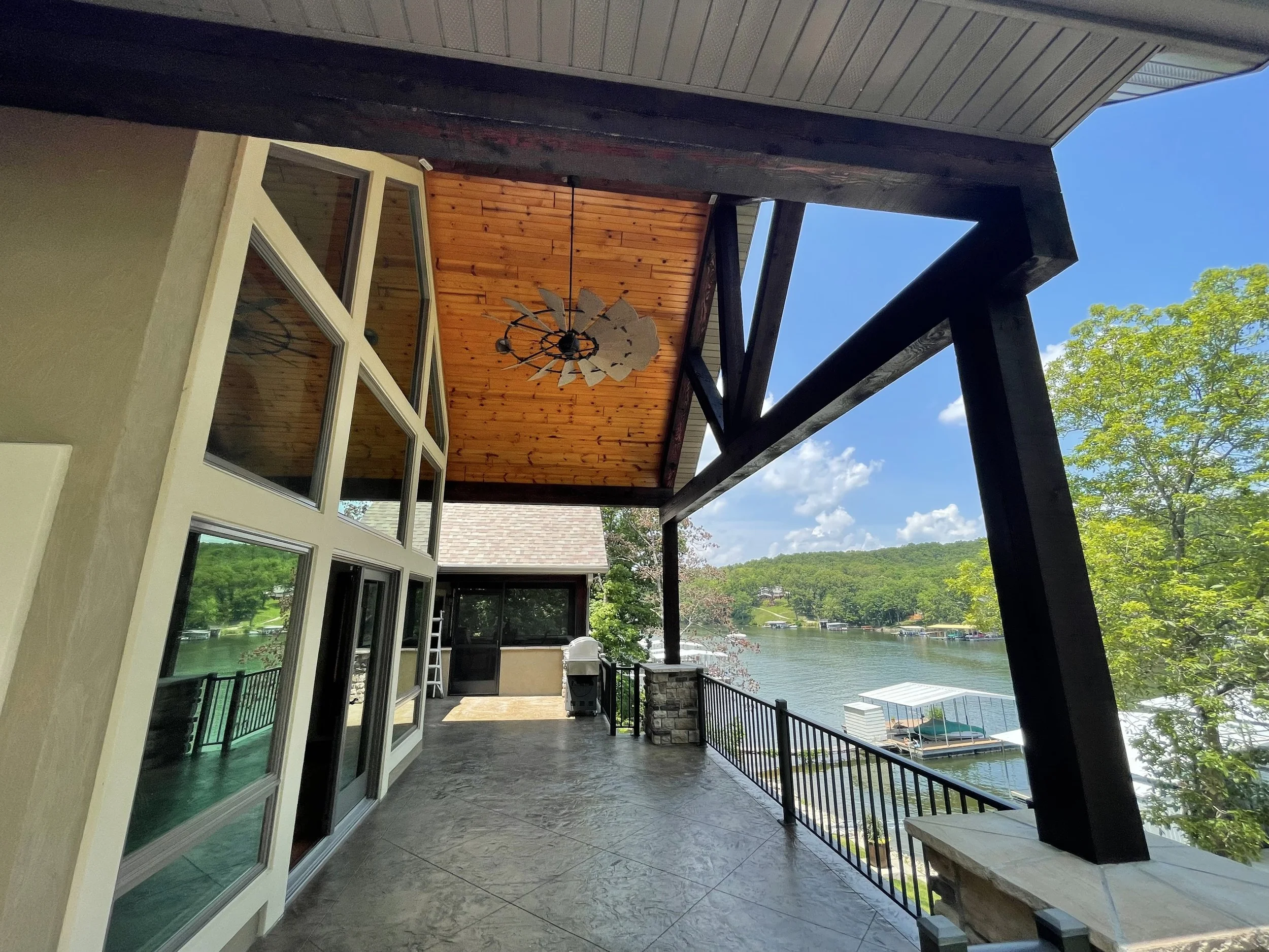 Walnut-stained tongue and groove deck ceiling with white painted beams by Quality Control Painting in Osage Beach.