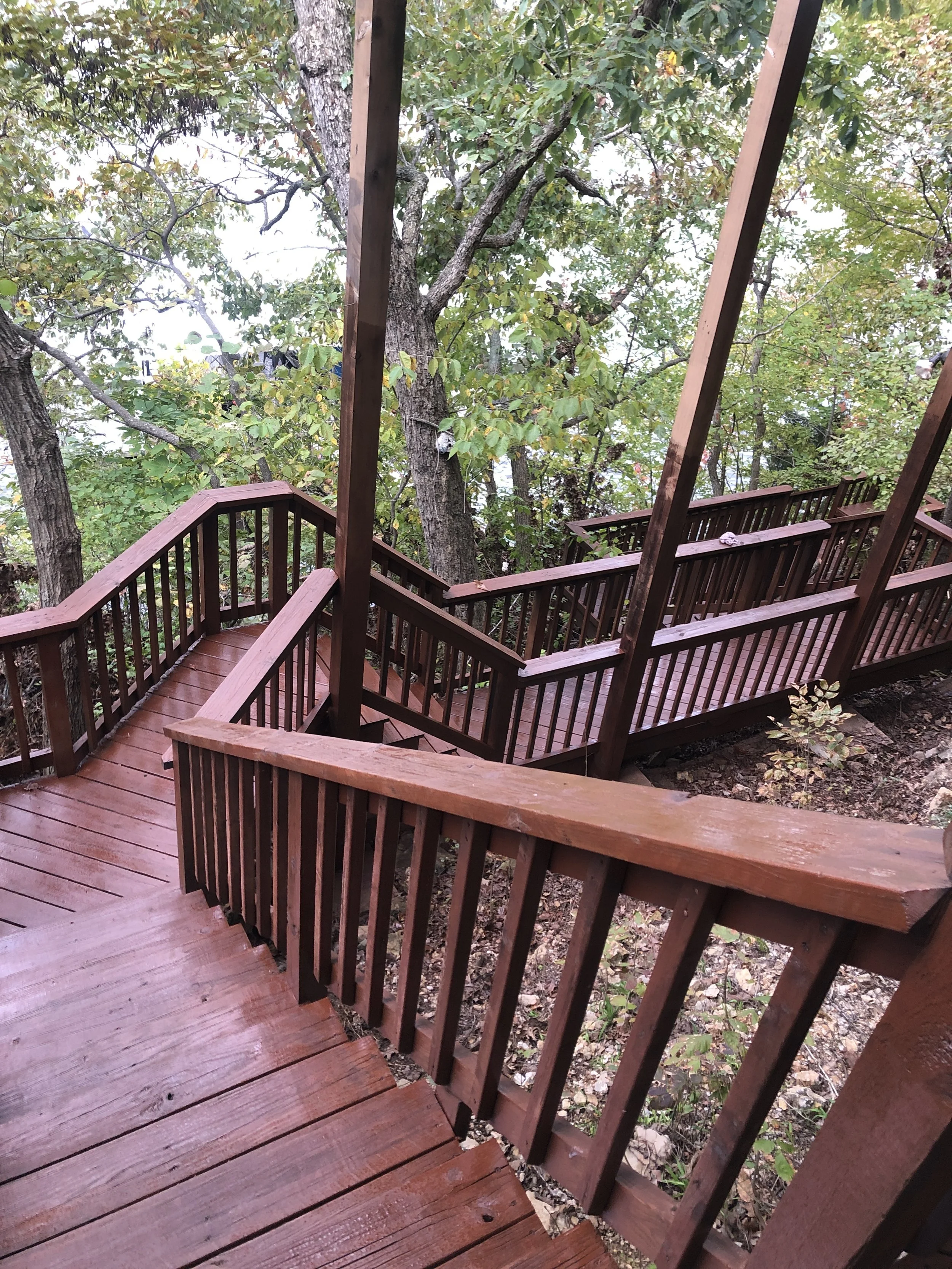 Large multi-tier deck winding through trees, professionally painted by Quality Control Painting in Lake Ozark.