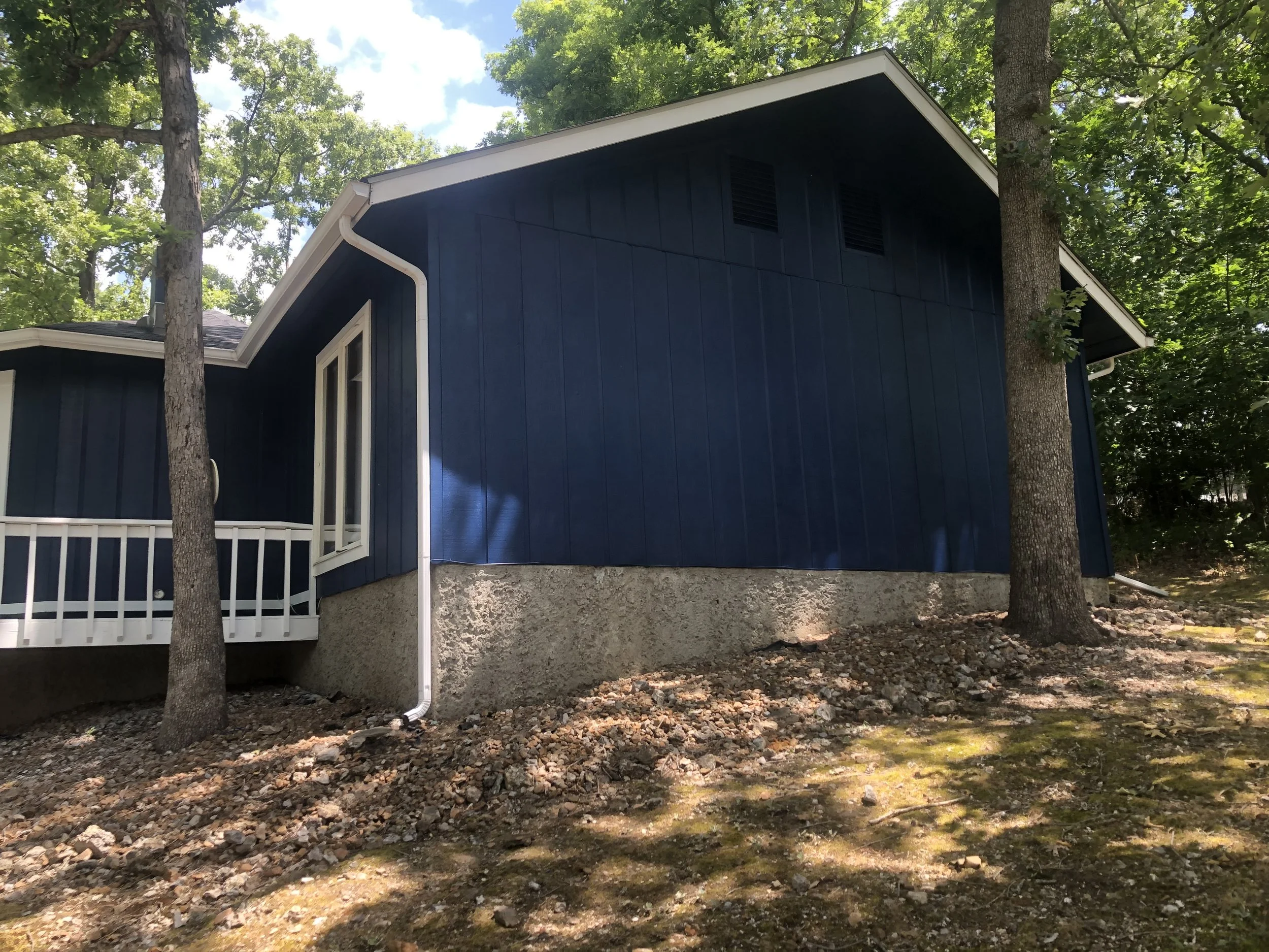 Close-up of professional white fascia, soffit, and trim painting against navy siding by Quality Control Painting in Osage Beach.