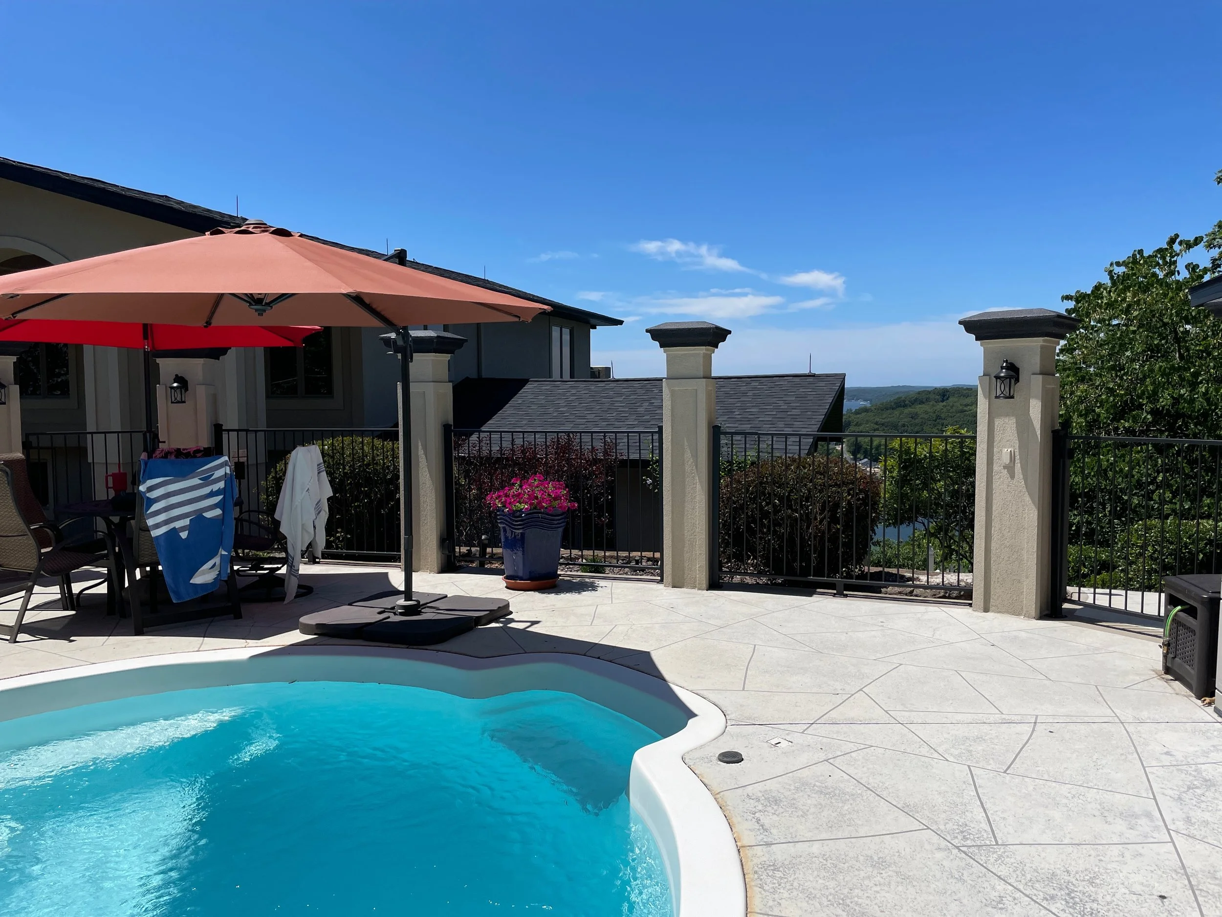 Black metal safety fencing and decorative pillars painted by Quality Control Painting at an Osage Beach pool area.