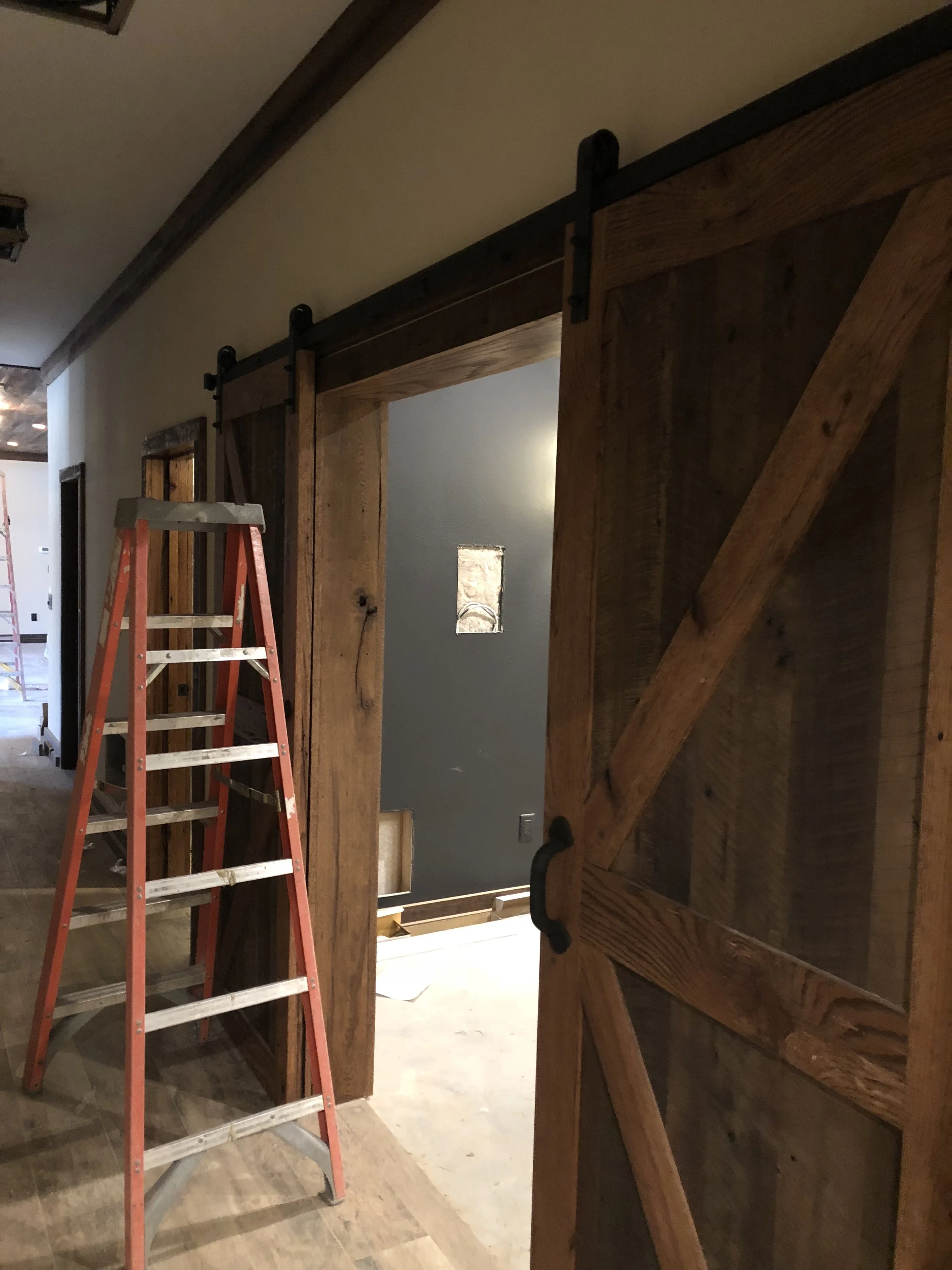 Rustic barn doors with freshly painted dark trim and a charcoal accent wall completed by Quality Control Painting in Osage Beach.