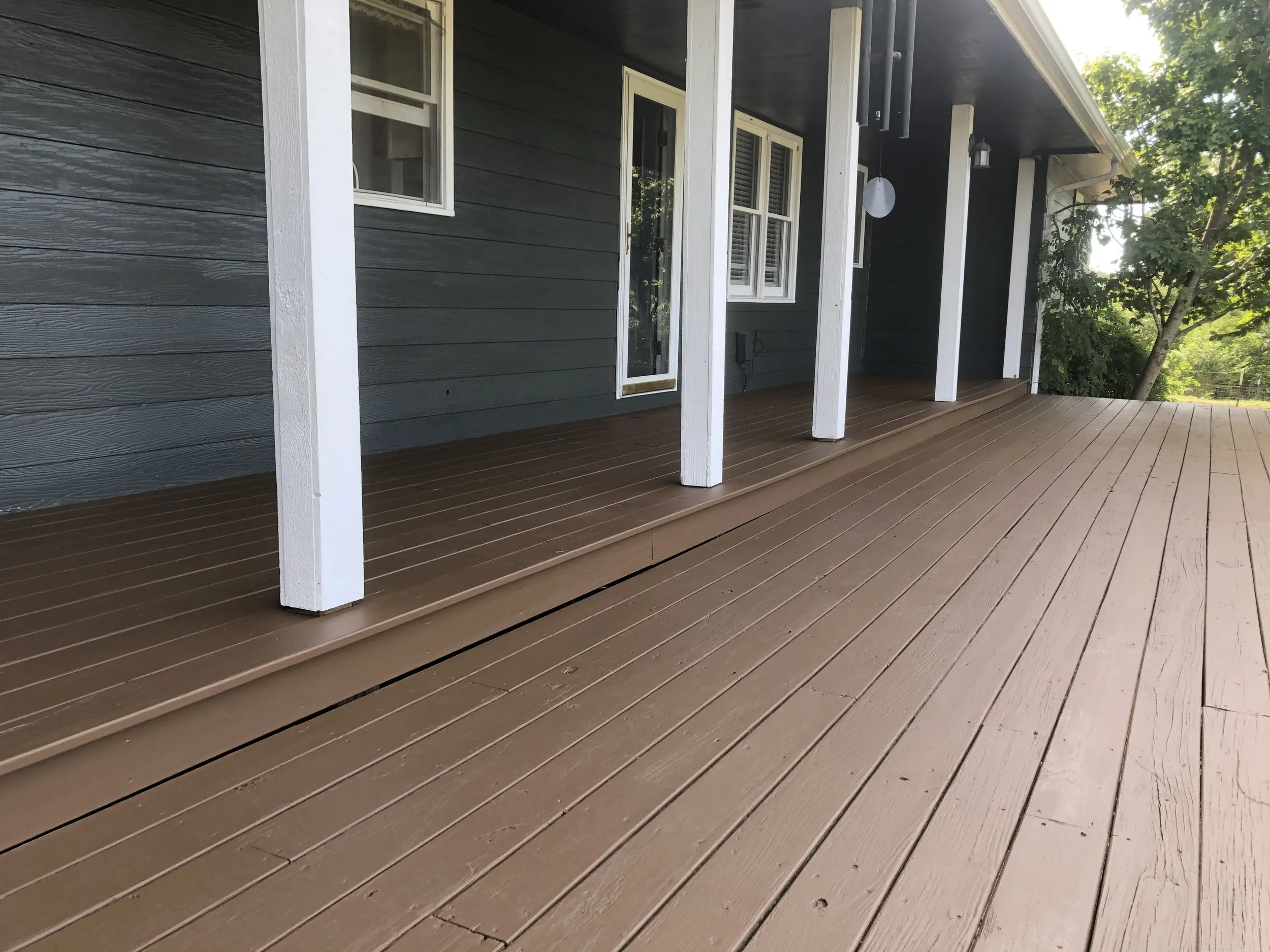 High-elevation wooden deck featuring a solid-color stain for weather protection by Quality Control Painting in Camdenton.