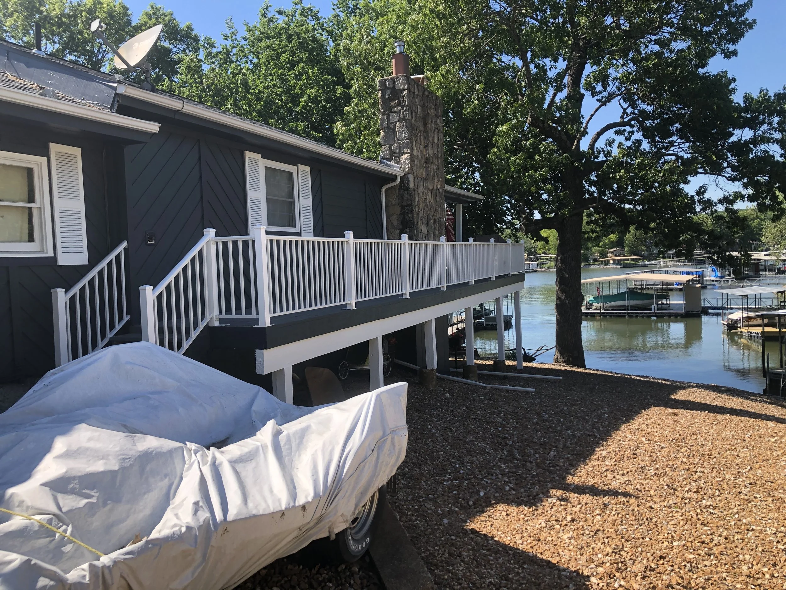 Detail of freshly painted white wooden deck railings against navy siding, a project by Quality Control Painting in Lake Ozark.