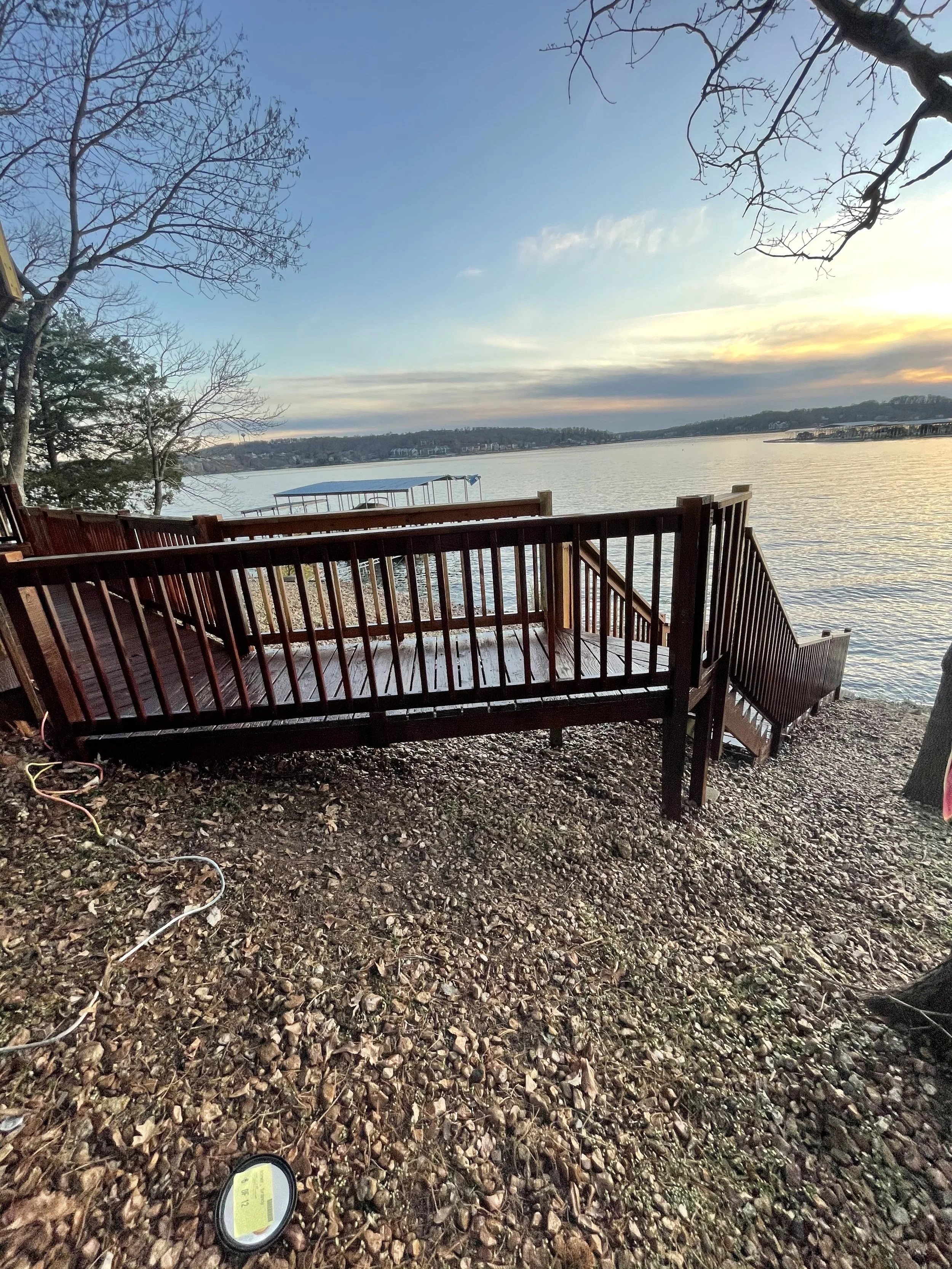 Dark mahogany wood deck and stairs stained by Quality Control Painting on a rocky Lake of the Ozarks shoreline in Laurie.