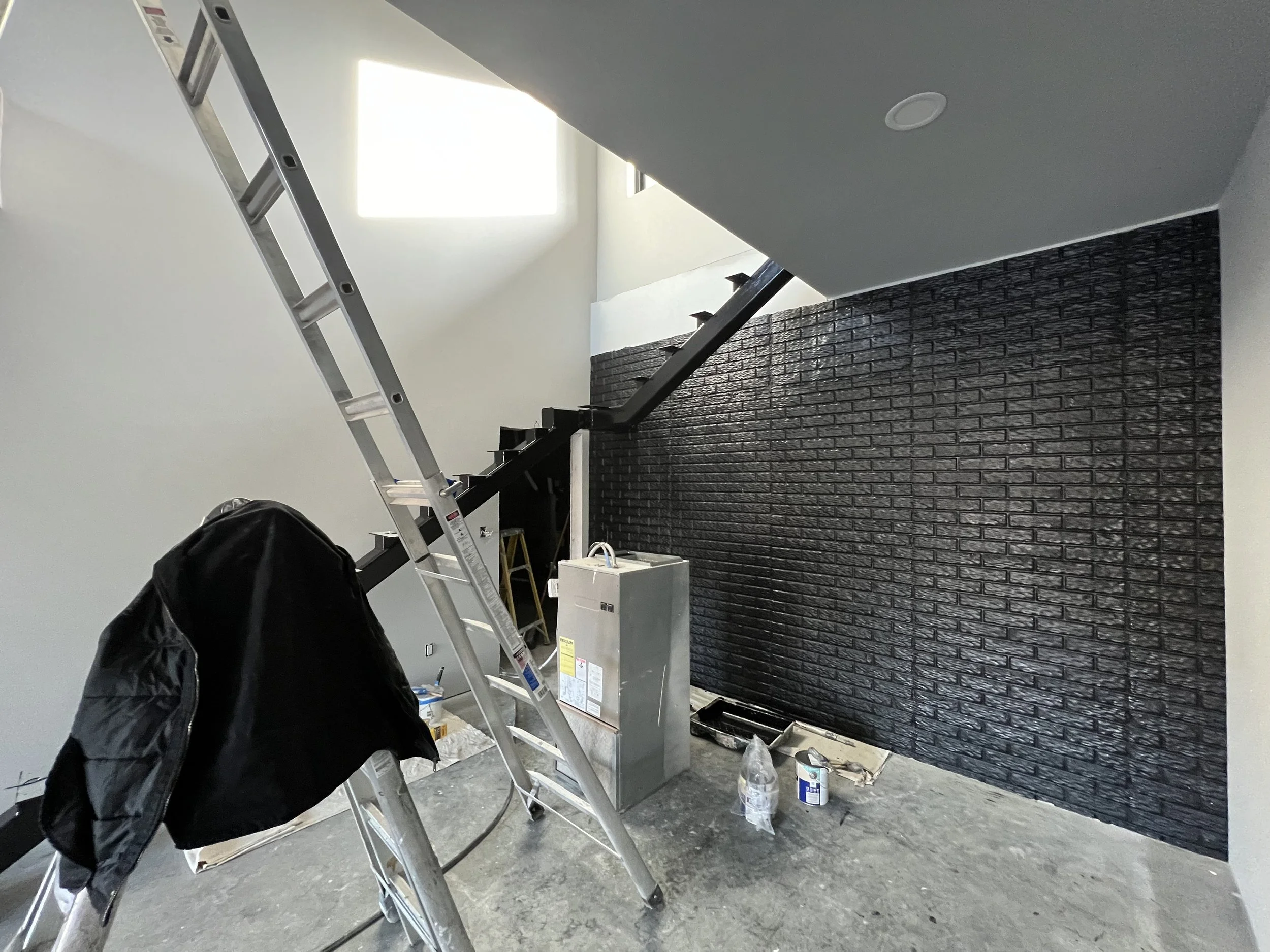 Textured black brick accent wall and metal staircase frame painted by Quality Control Painting in a Camdenton remodel.