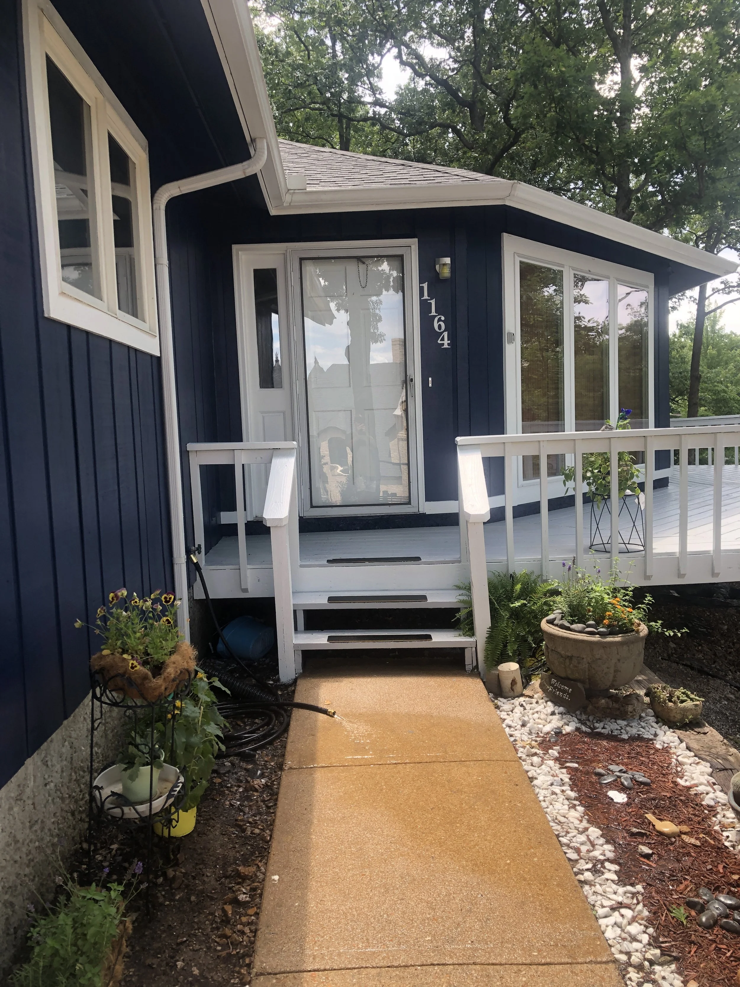 Lakeside home featuring navy blue siding and white trim painted by Quality Control Painting in Osage Beach.
