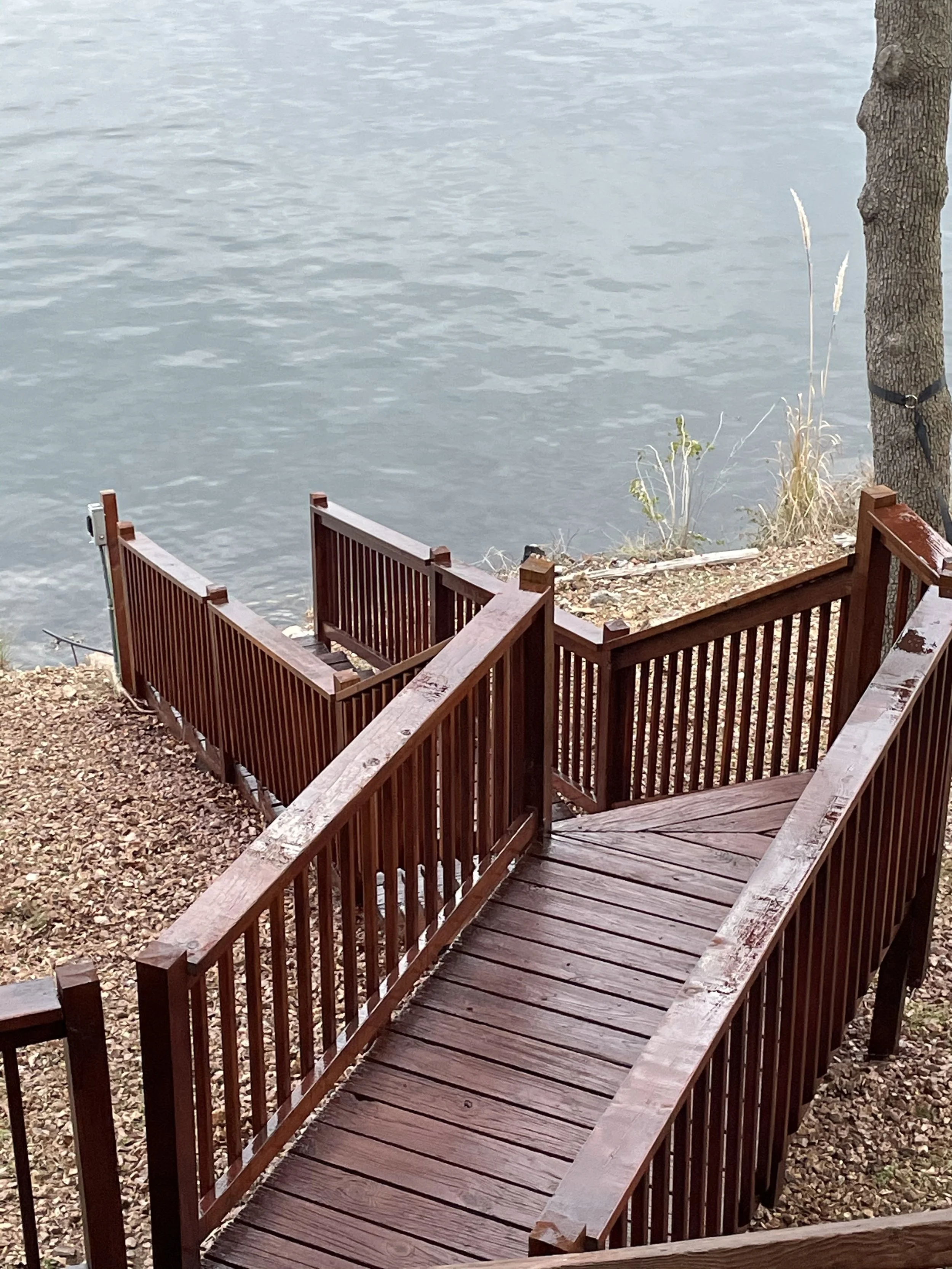 Detailed view of mahogany stained wooden stairs on a steep lakefront slope in Camdenton by Quality Control Painting.