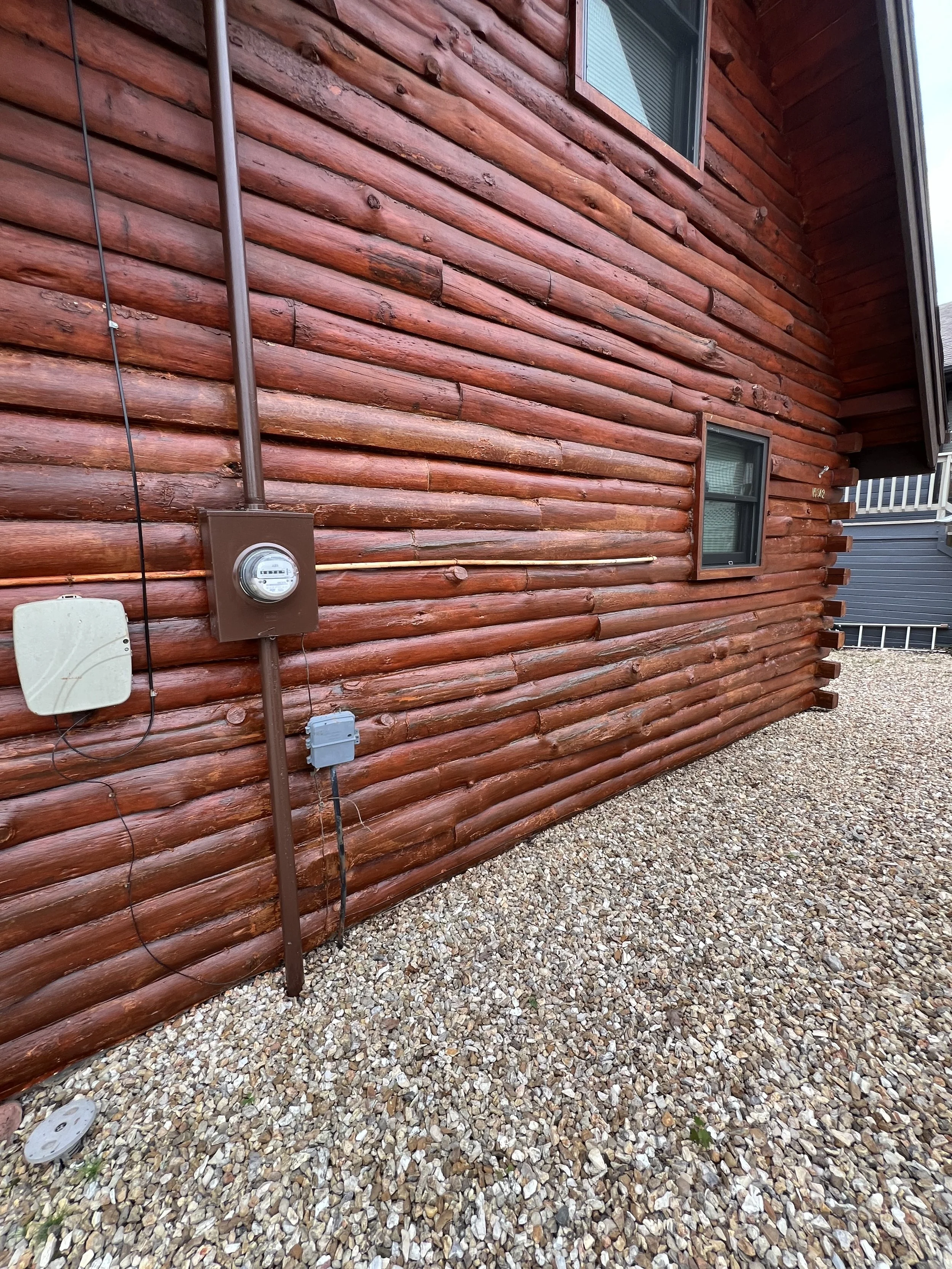 Detailed view of freshly stained logs and clean white chinking lines on an Eldon cabin by Quality Control Painting.