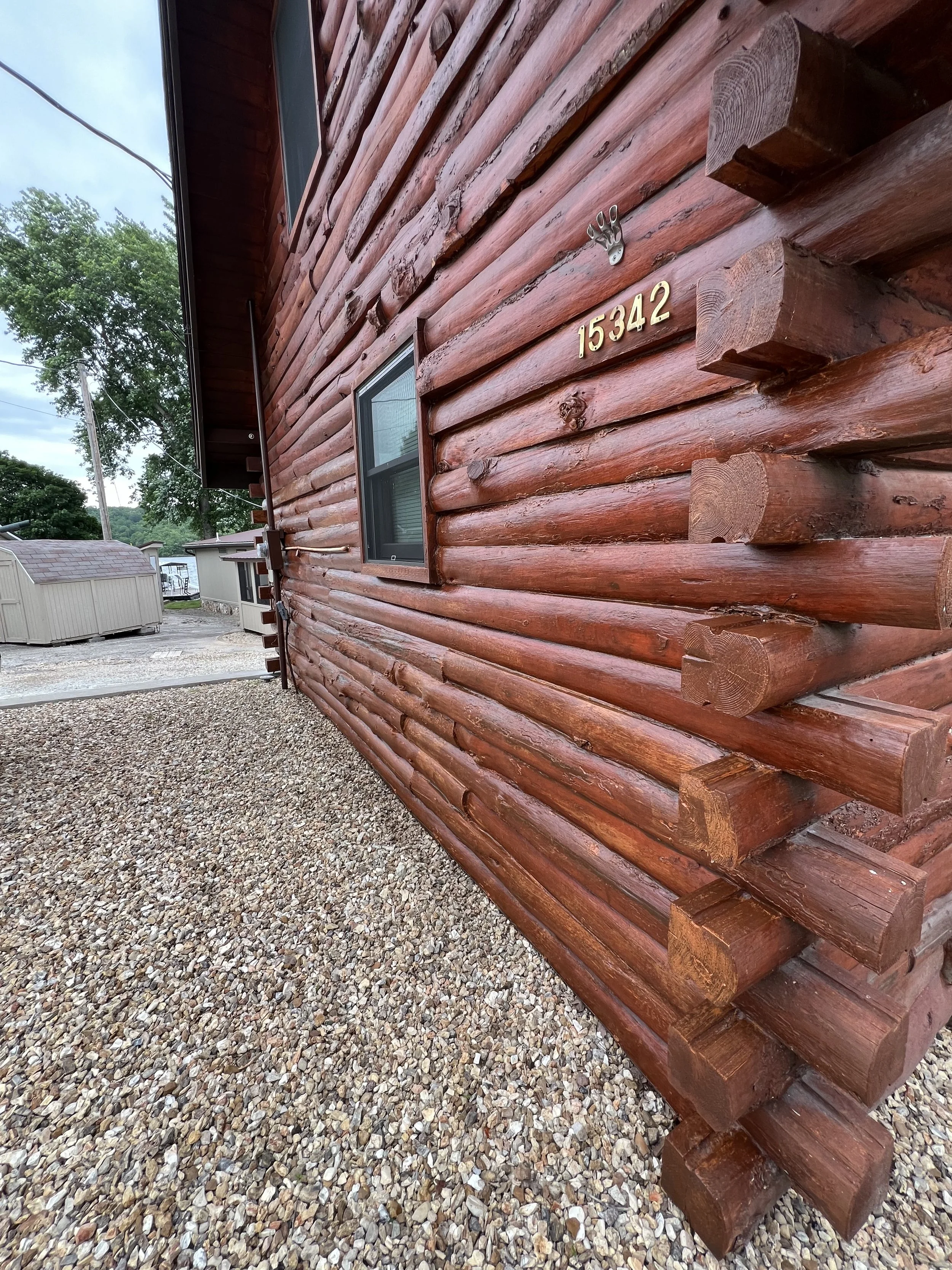 Multi-story log cabin in Eldon featuring a honey-colored wood stain restoration by Quality Control Painting.