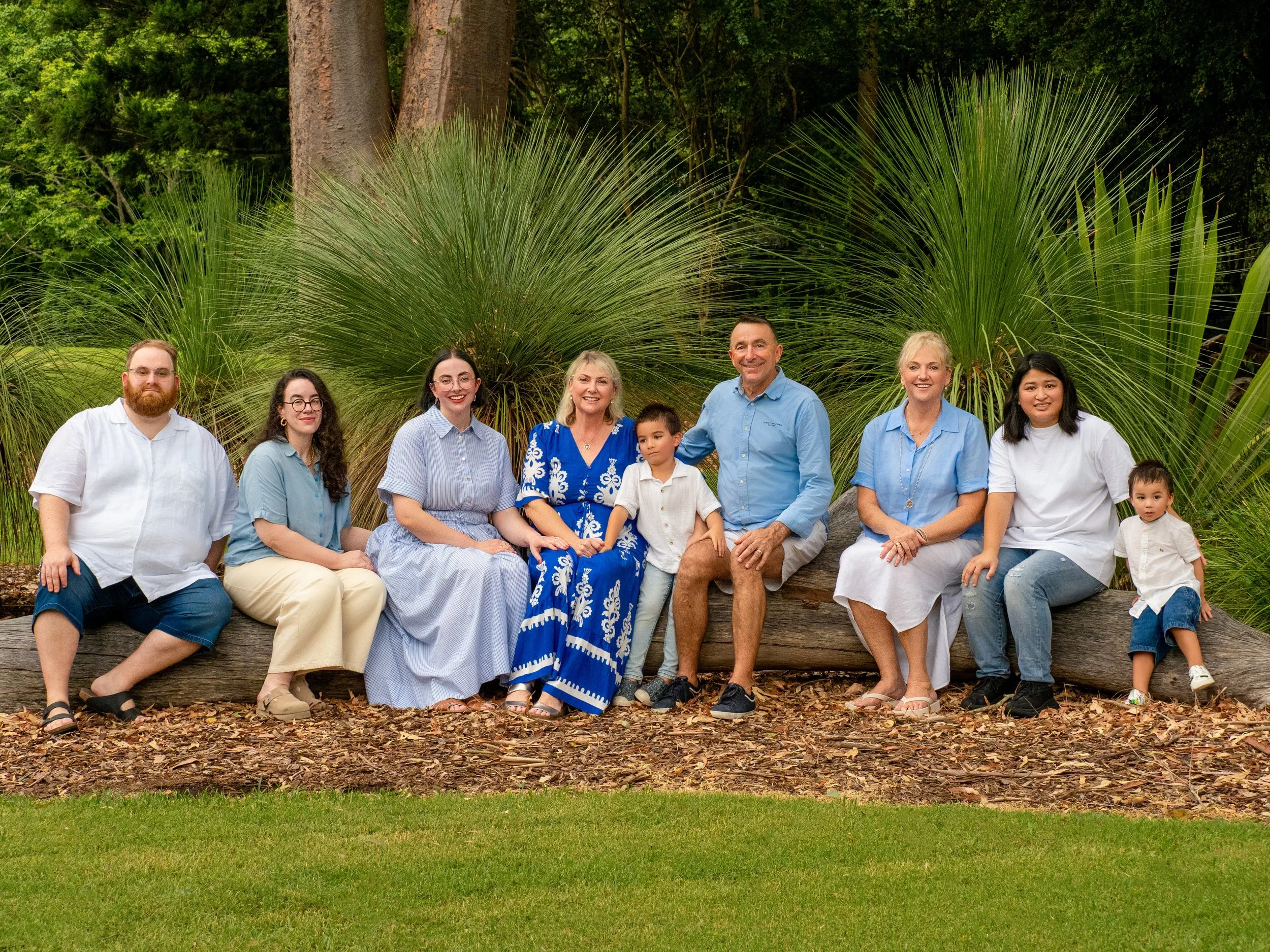 Extended family photo session in Ipswich with three generations sitting together on a log