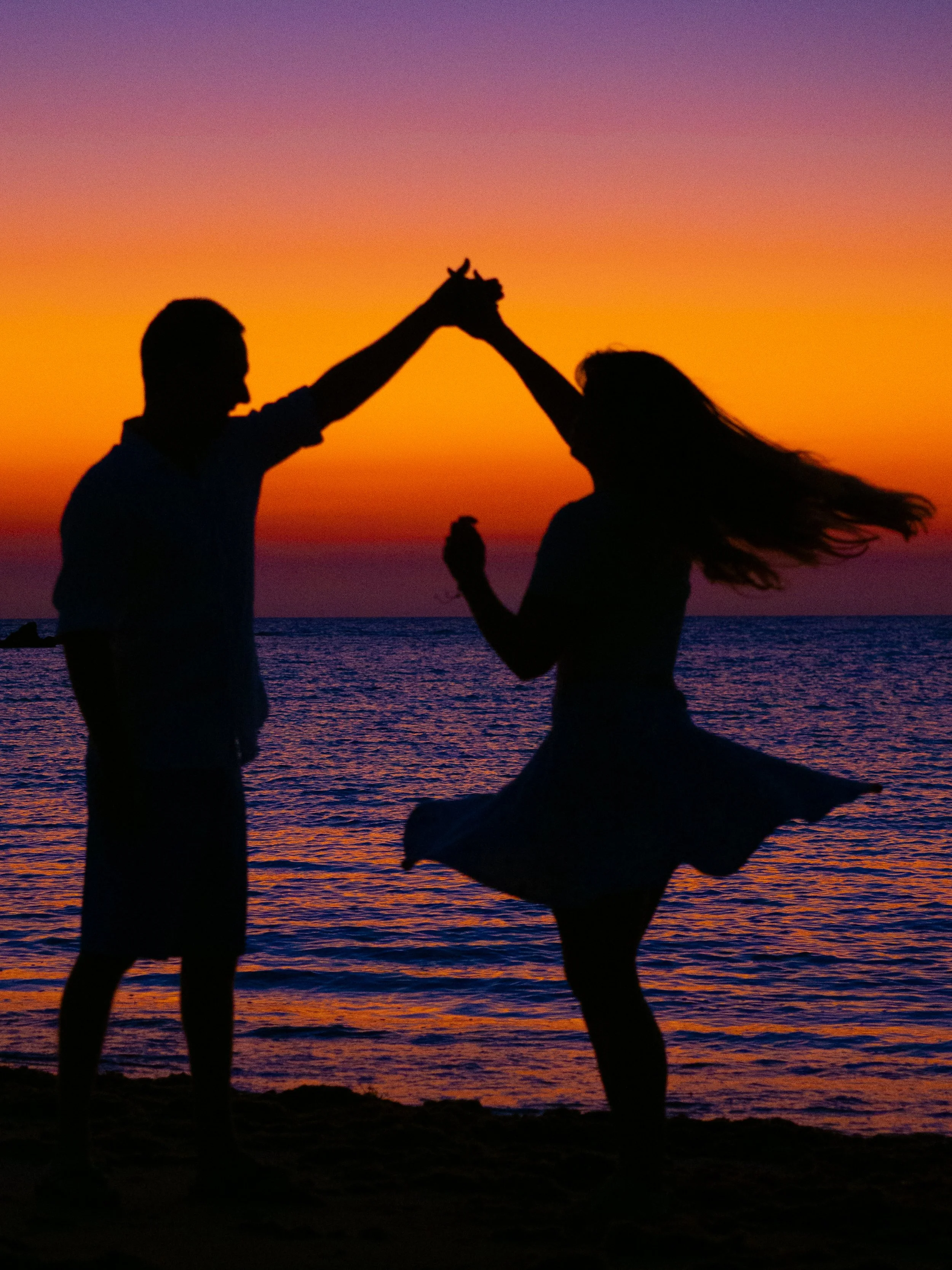 A silhouette of couple dancing on a vibrant purple beach