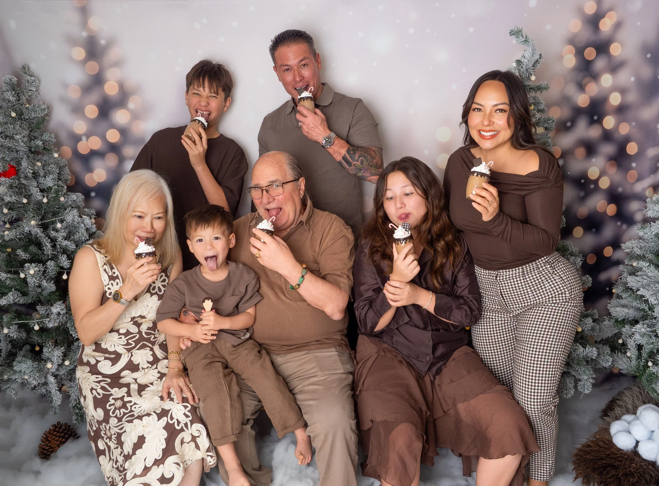 Multigenerational family with grandparents, parents, and grandchildren drinking hot chocolates together during Christmas family photos