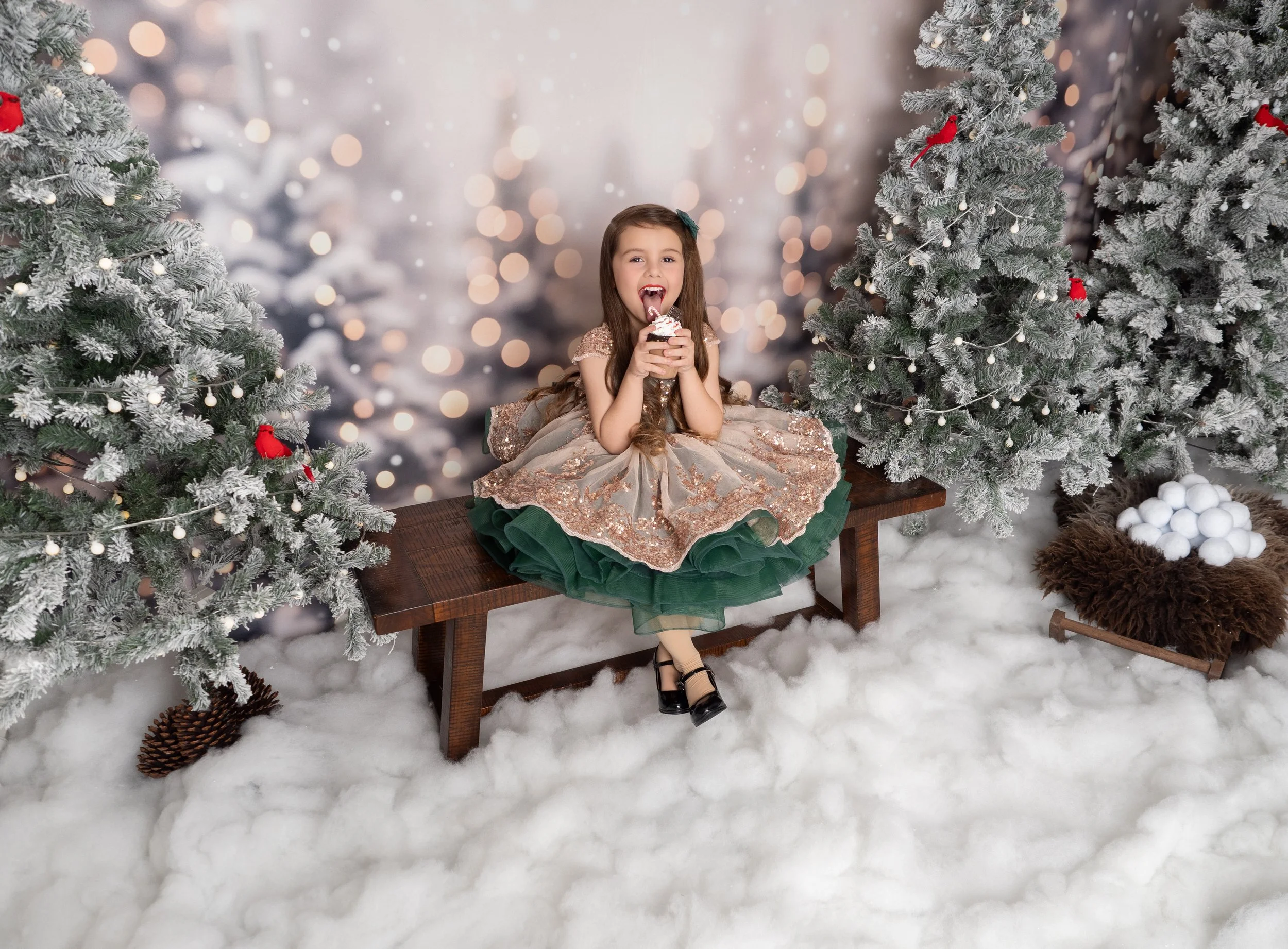 Young girl enjoying a Christmas treat on a bench in a snowy Winter Wonderland Christmas mini session