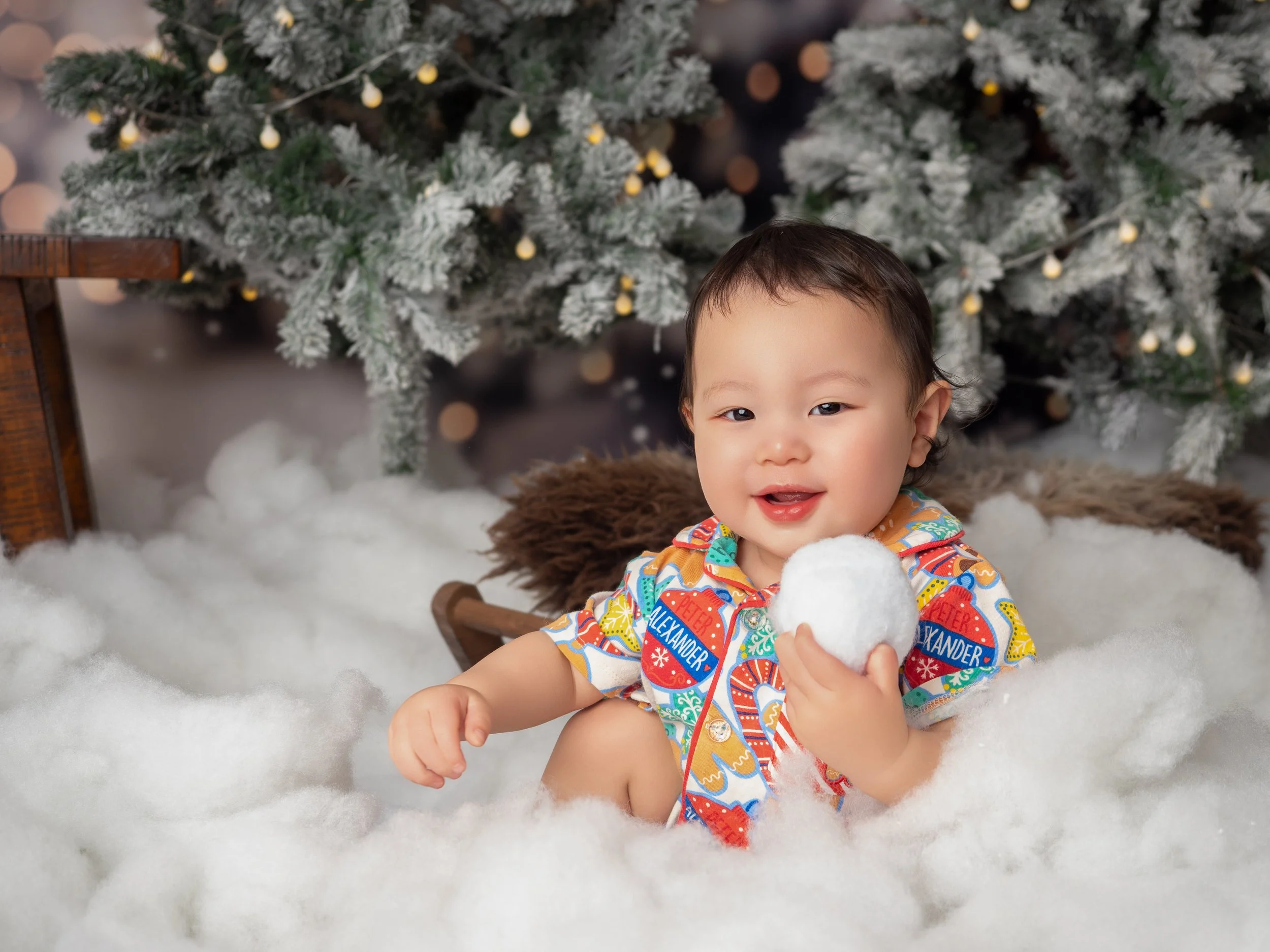 Baby holding a snowball during a playful Winter Wonderland Christmas mini session