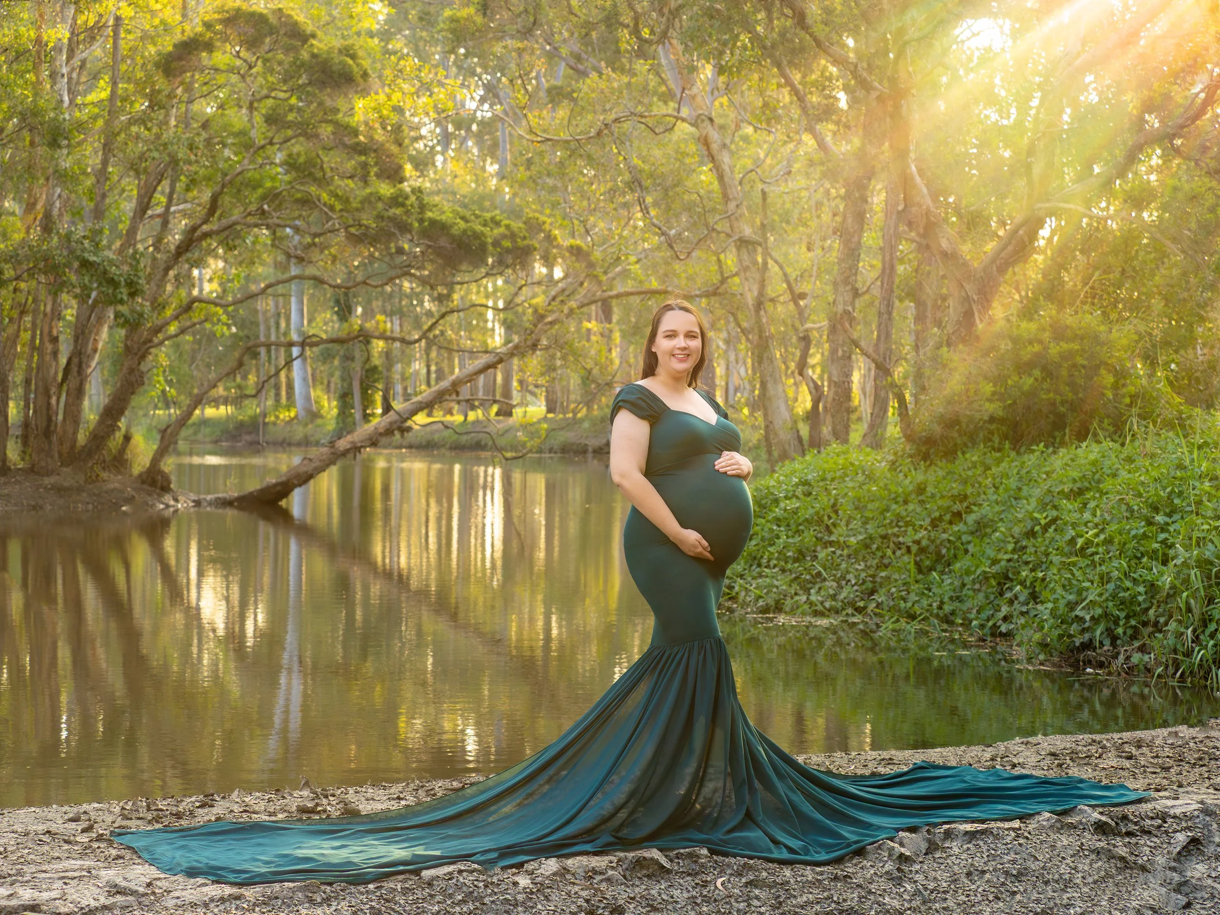 Expectant mother holding her belly in a maternity session near a Logan lake.