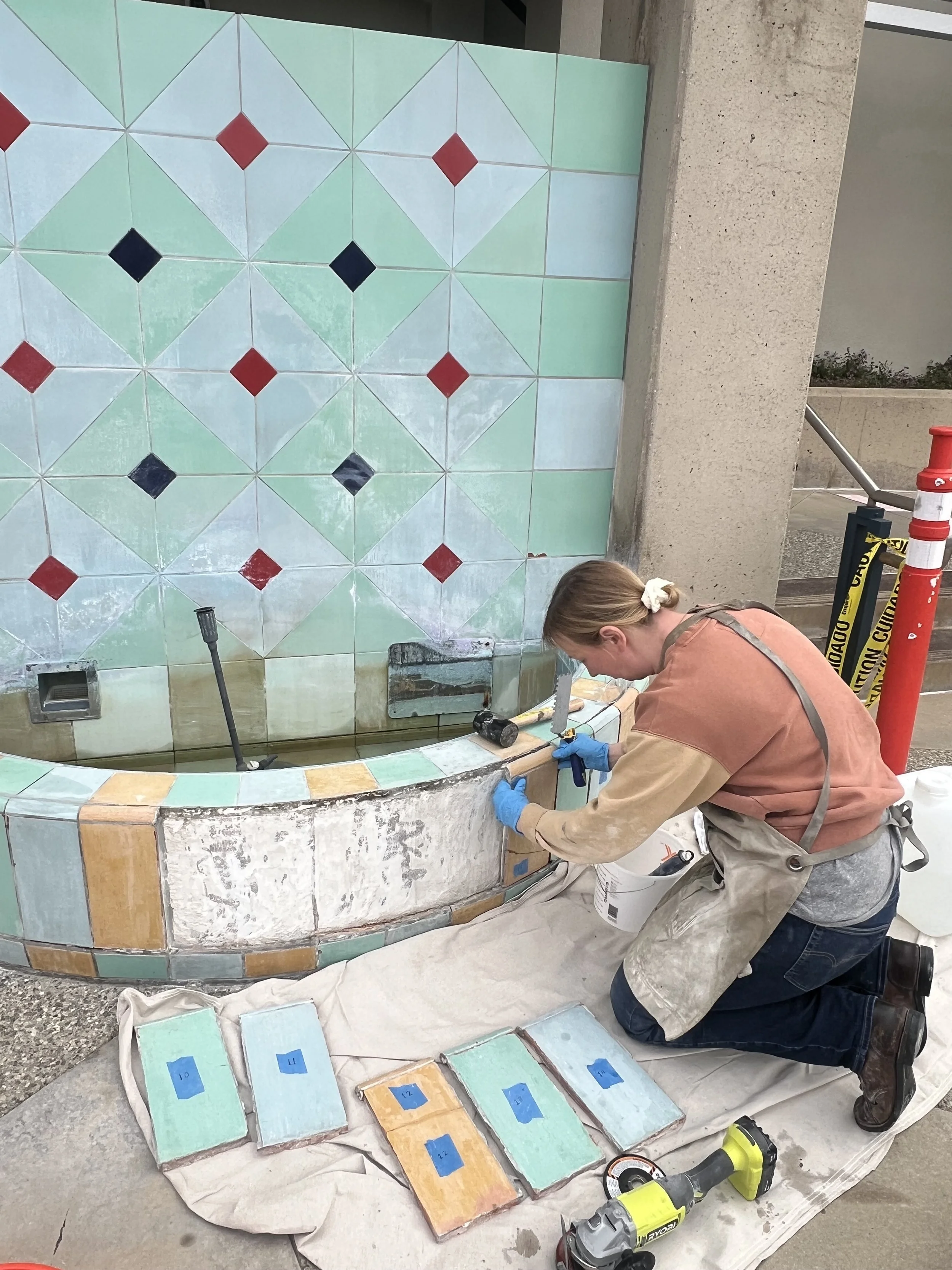 A conservator is filling cracks in the original tiles and in color matching paint and glaze to in-paint.