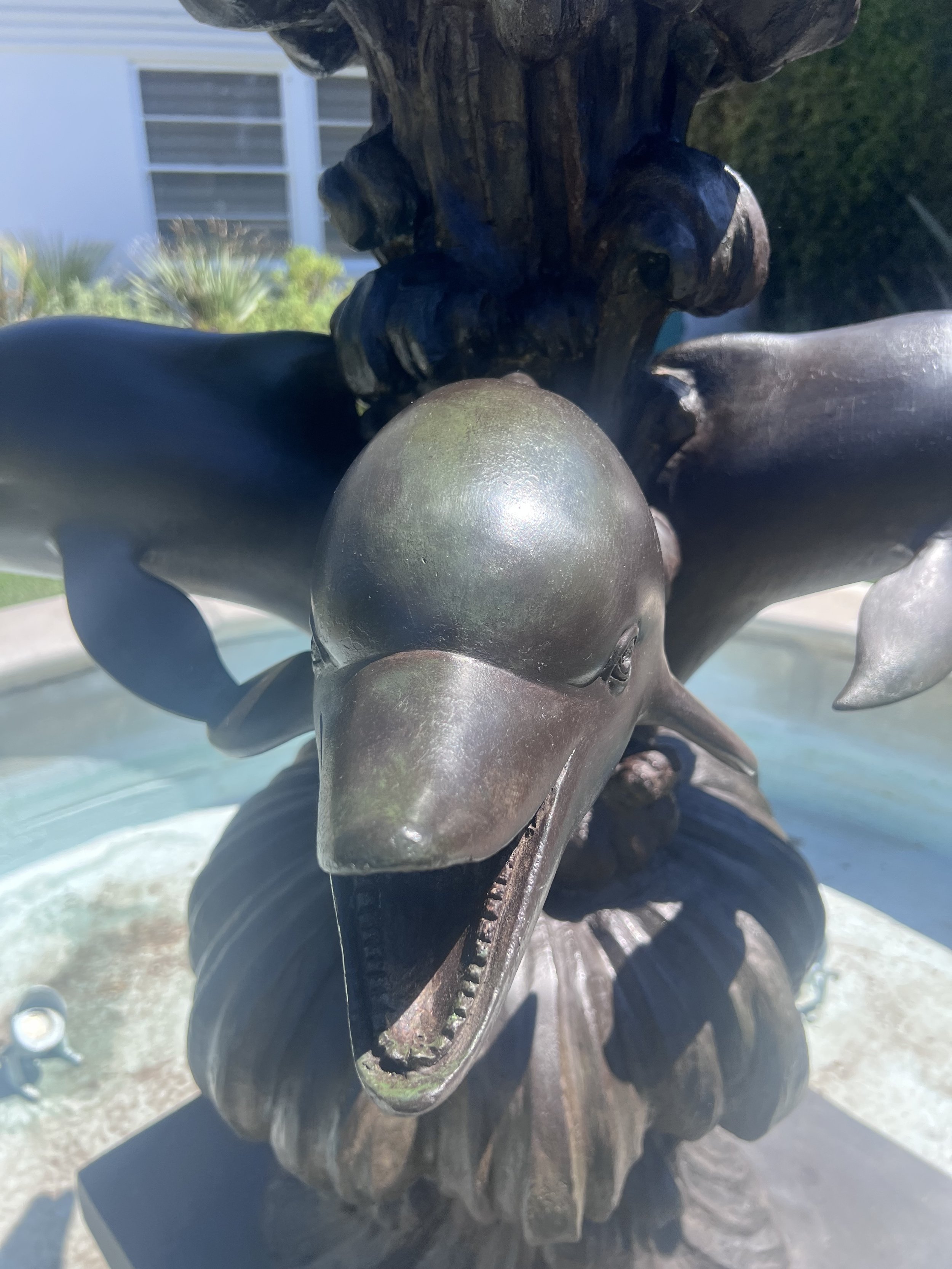 Close-up of a bronze sculpture of a girl with a dog, with a ball in the foreground. Background shows a building and some trees.