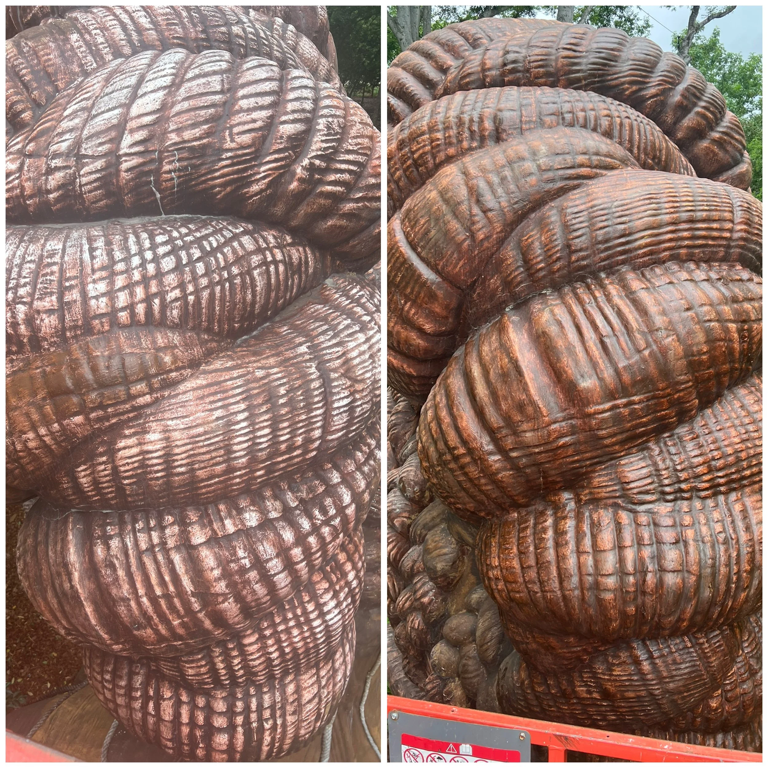 Close-up of a large, carved wooden sculpture with detailed texture, set outdoors with trees in the background.