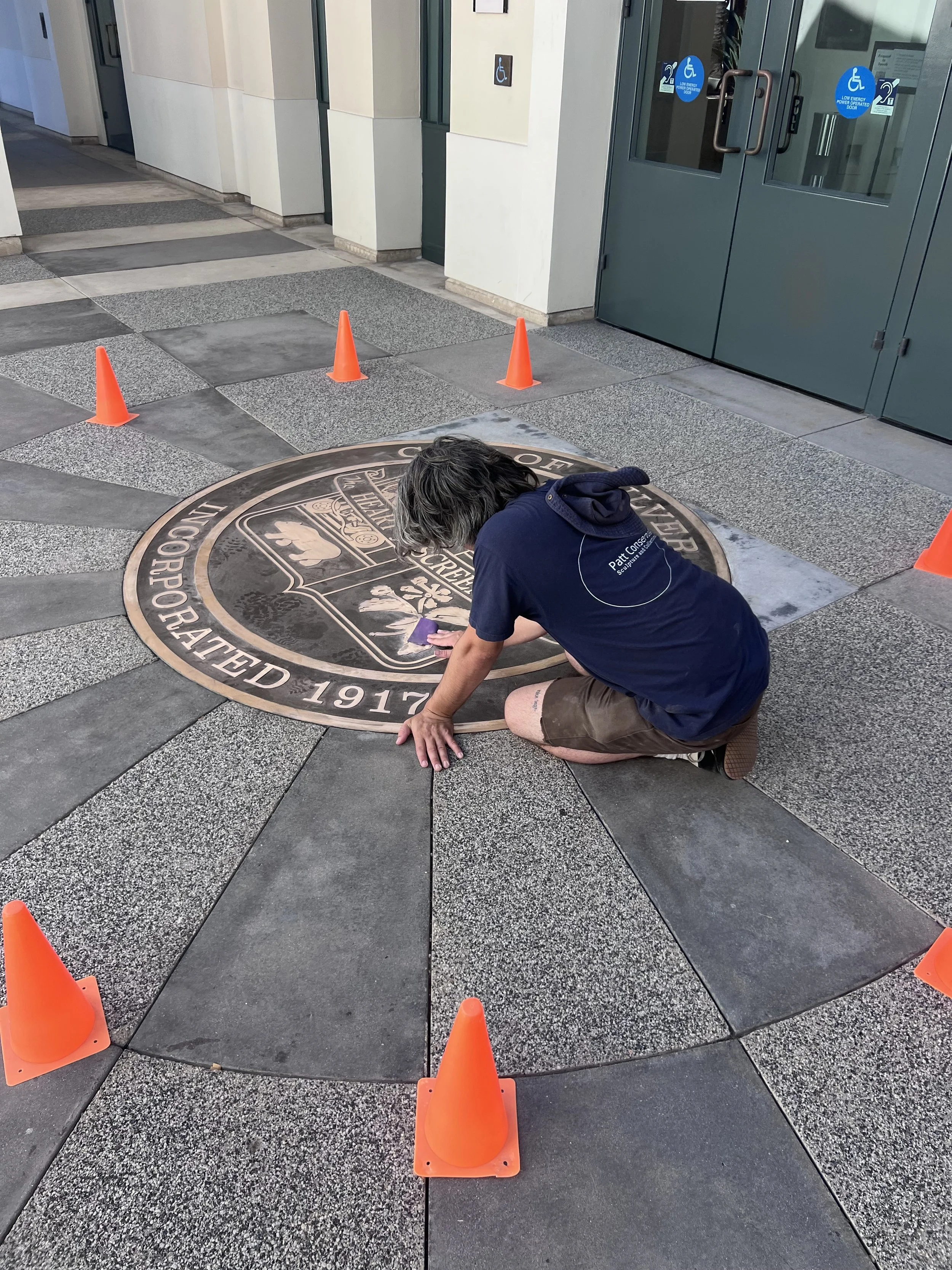 Zach Blair from Patt conservation working on a bronze city seal plaque.