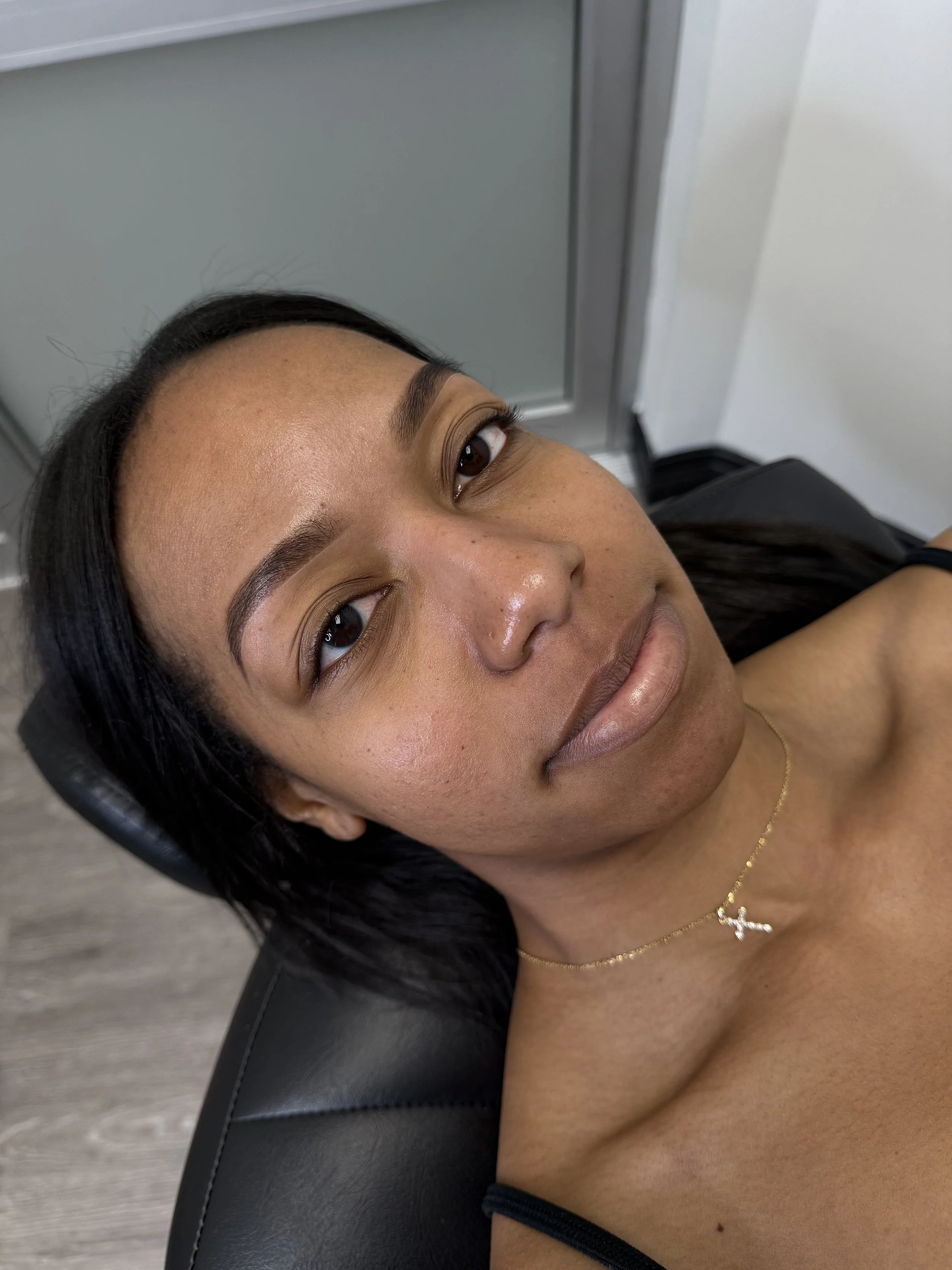 Close-up of woman lying back in a chair, looking at the camera, with neatly shaped eyebrows.