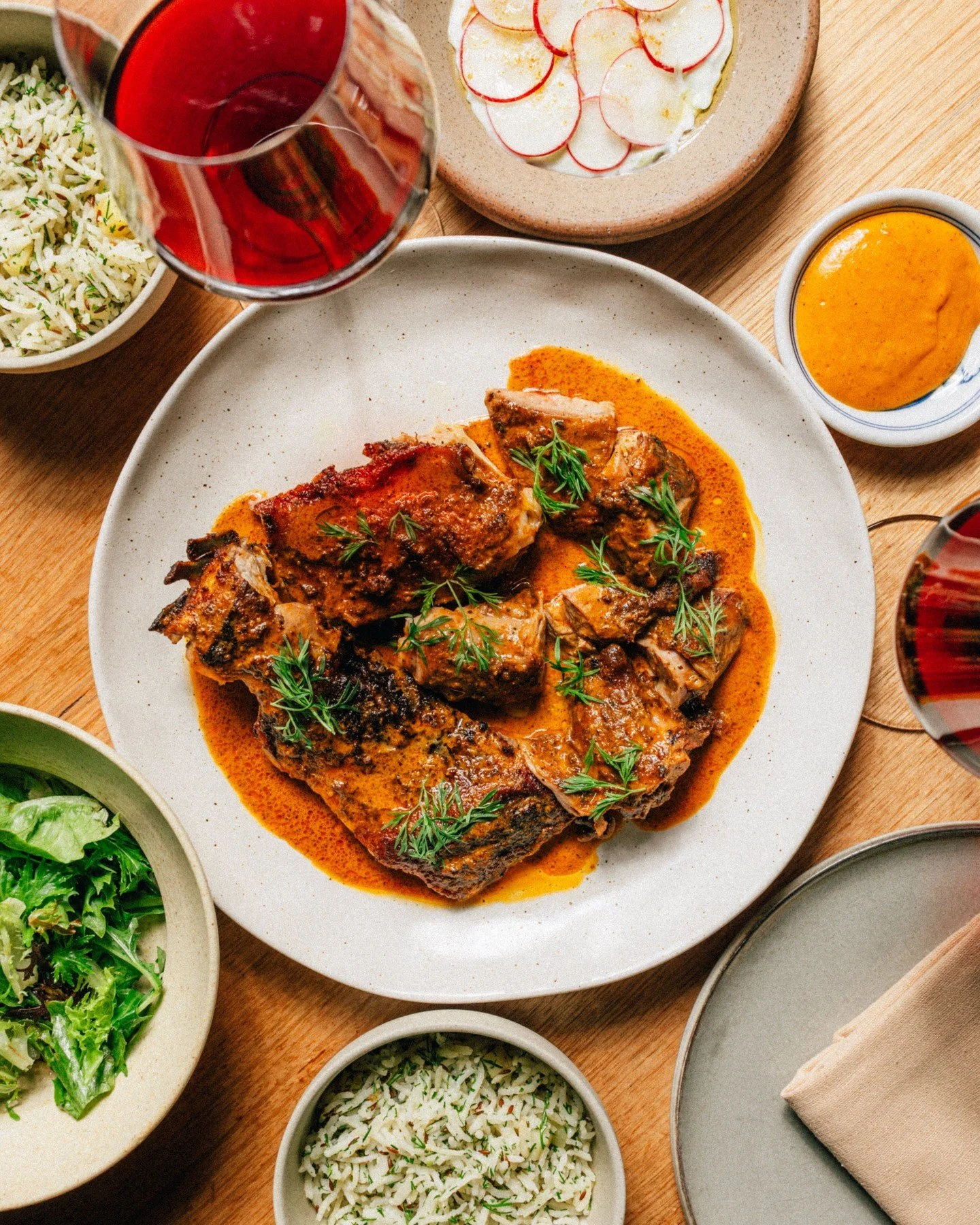 Tender @meredithfarmproduce goat is spit-roasted over the fire. Served with Lime Achaar, Pulao, Cucumber and Radish Raita, plus a clean green salad. Our NYE showstopper is bound to turn heads, we promise!